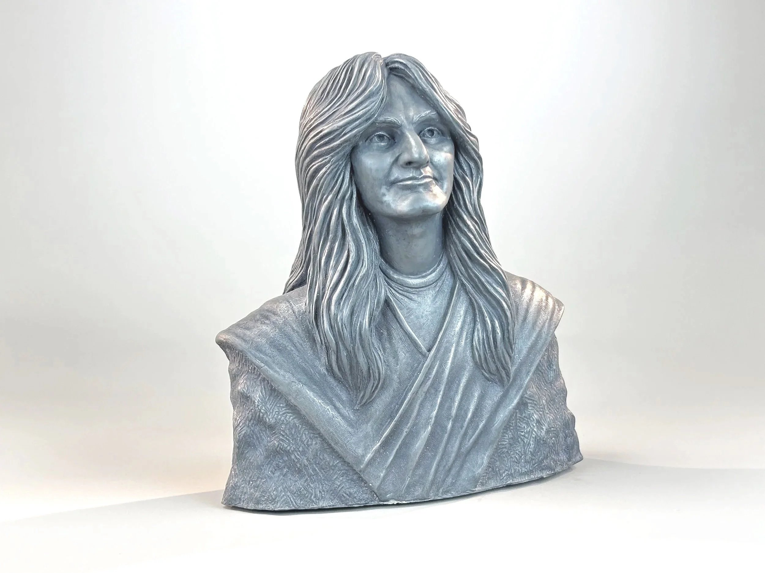 A metallic bust sculpture of Geddy Lee (circa 1977) displayed against a plain white background.