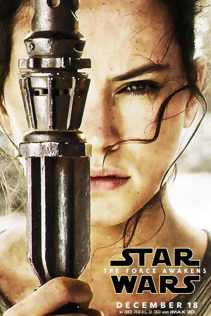 Close-up of a female character holding a lightsaber with a metallic hilt, from the movie 'Star Wars: The Force Awakens'.