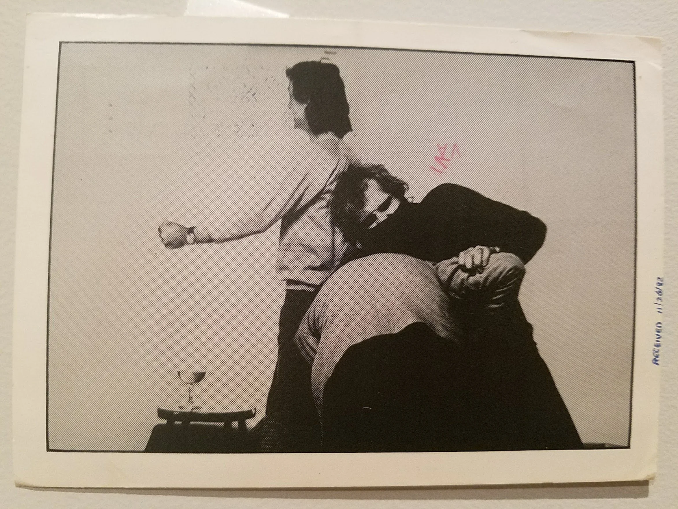 Black and white photograph of a woman sitting on a stool, using a stethoscope on a patient's back, with a table nearby.