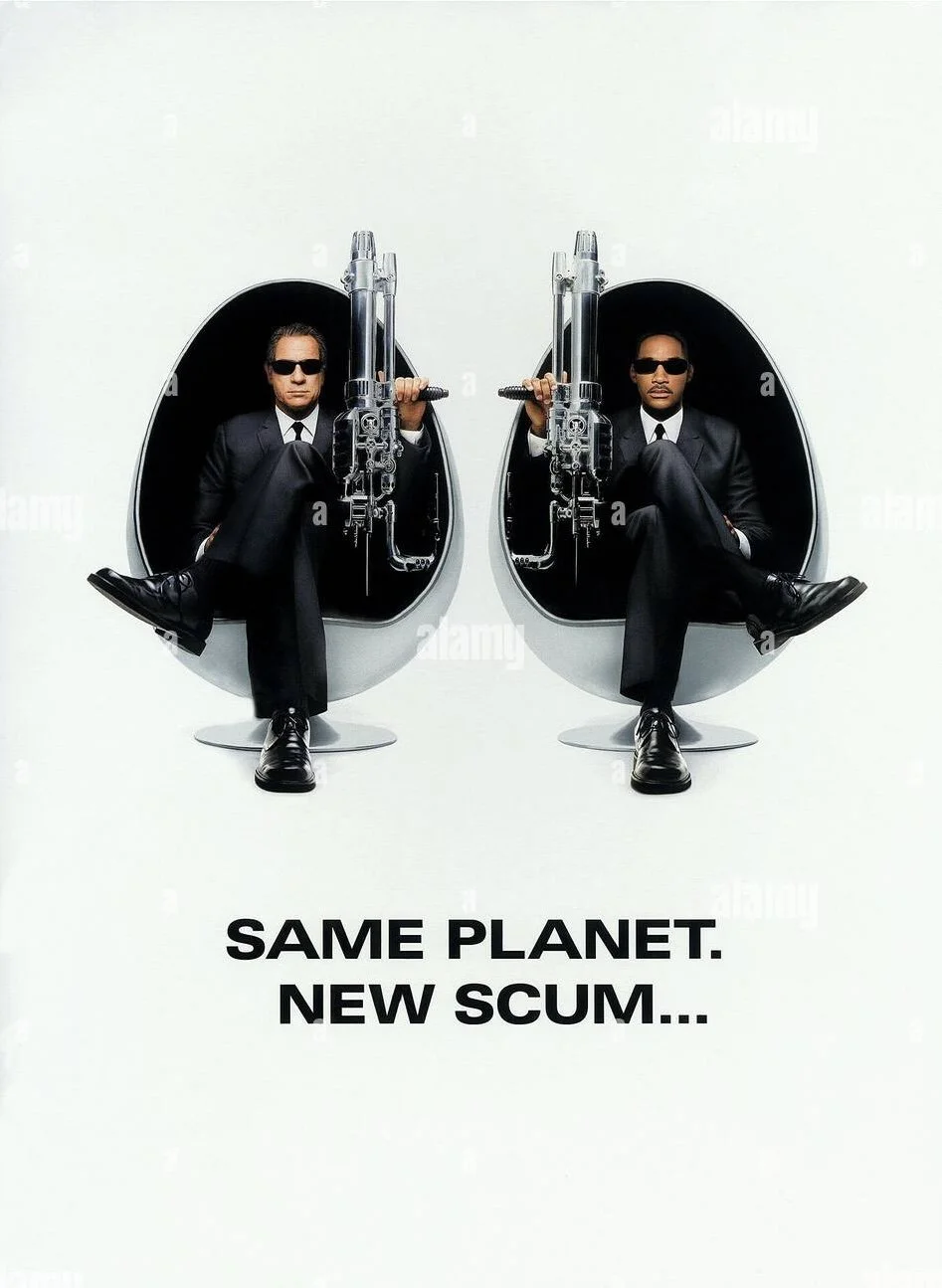Two men in black suits, sunglasses, sitting in futuristic egg-shaped chairs, holding guns. The text below reads 'Same Planet. New Scum...'