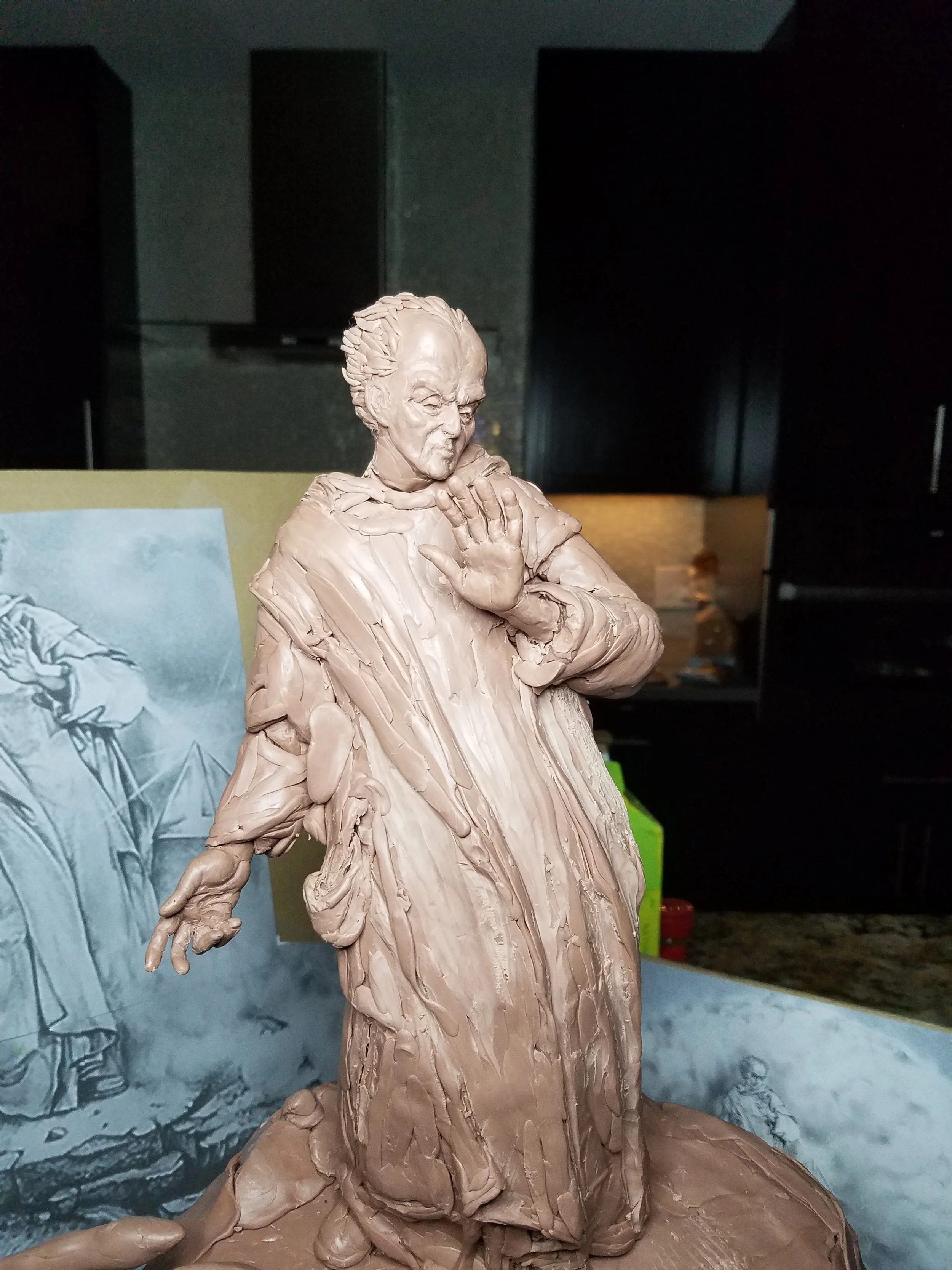 Clay sculpture of a woman with her hand on her chest, holding a cloth; background features sketches of figures and art supplies.
