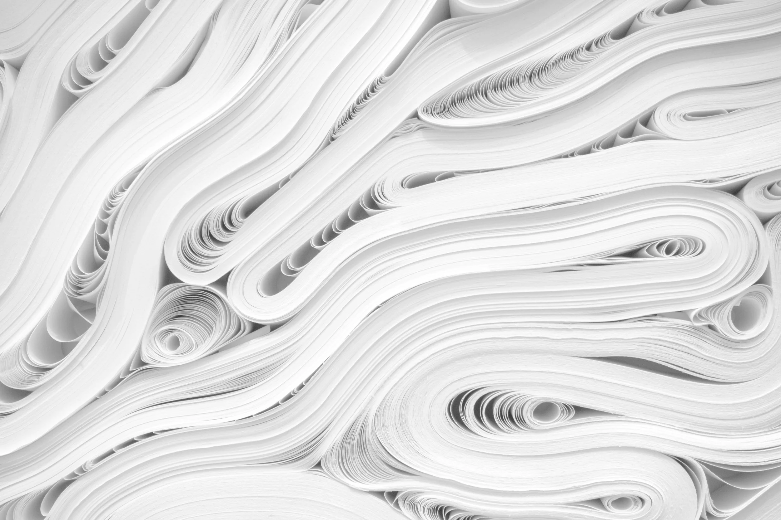 Close-up of neatly stacked, curled white paper sheets.