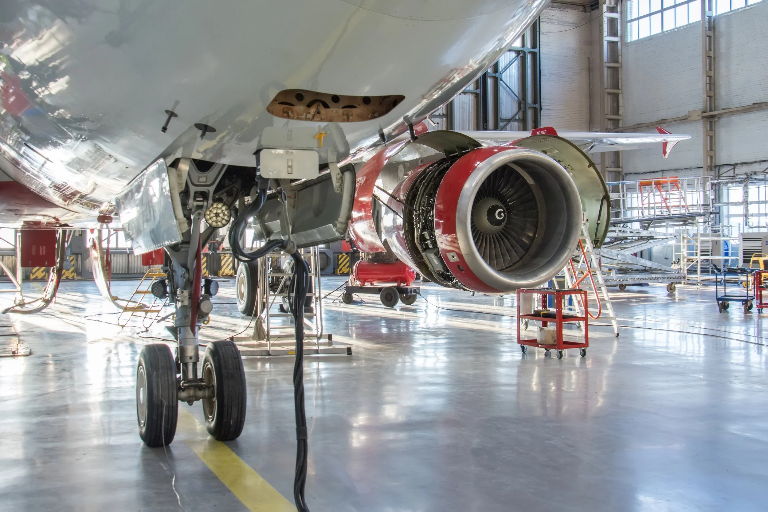 Aircraft in an airplane hangar with maintenance equipment around it.