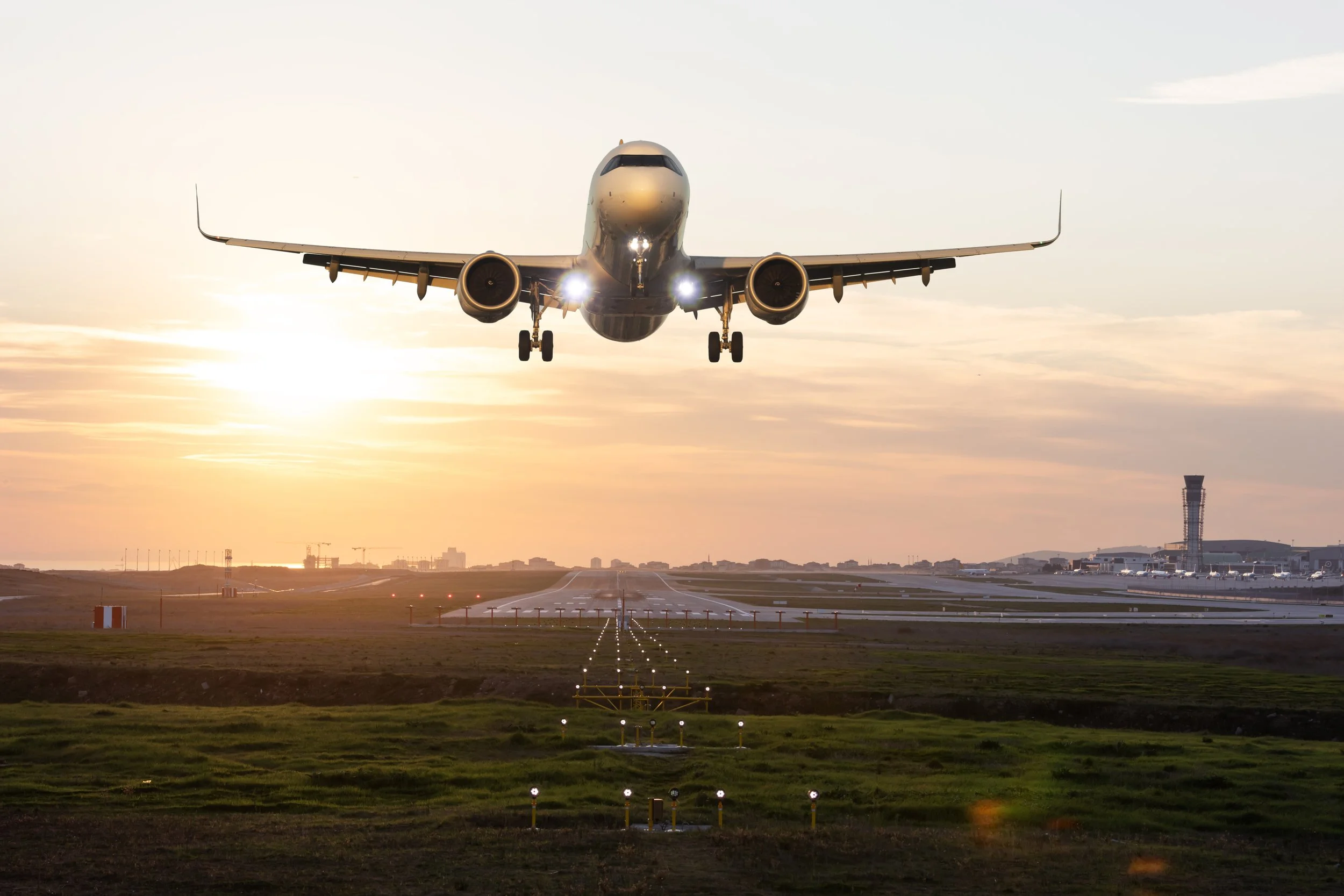 An airplane taking off at sunset from a runway.