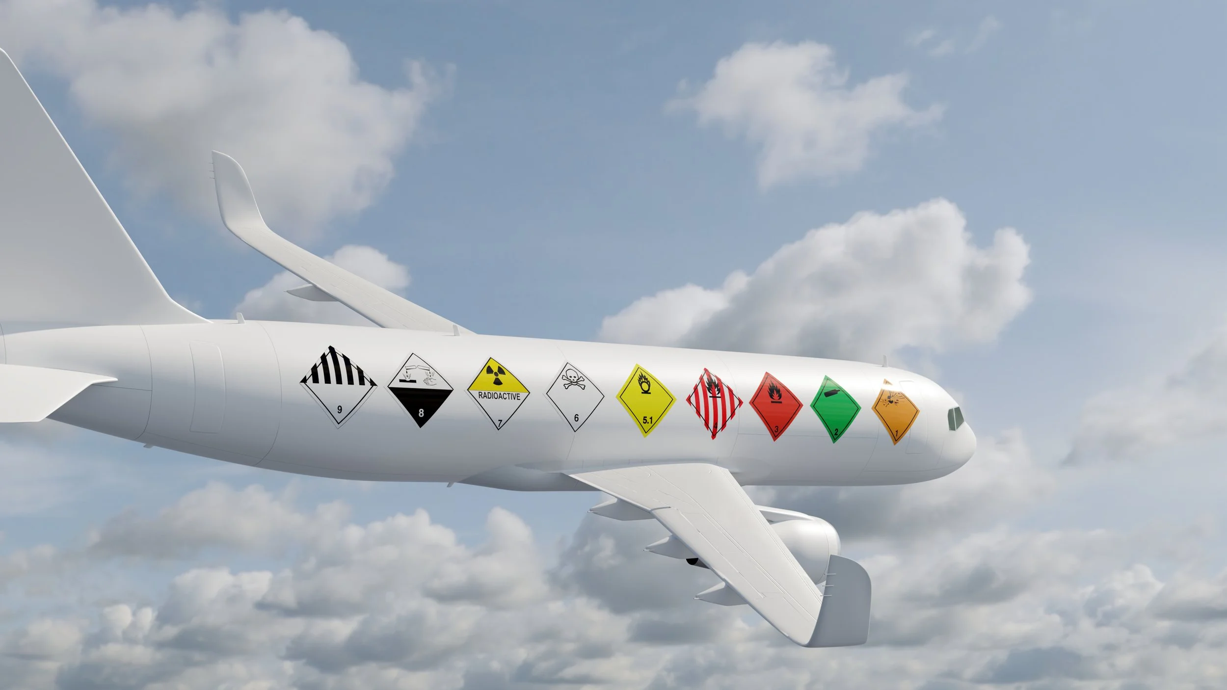 White airplane wing with hazard labels on the side flying in a cloudy sky.