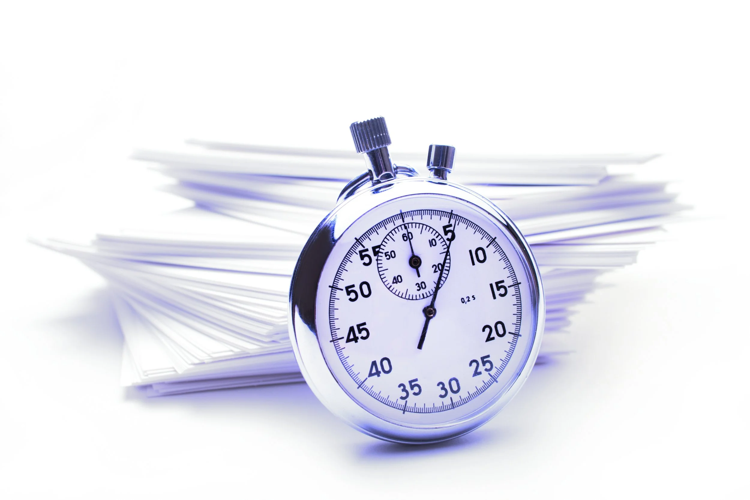 A stopwatch in front of a pile of white papers or documents.