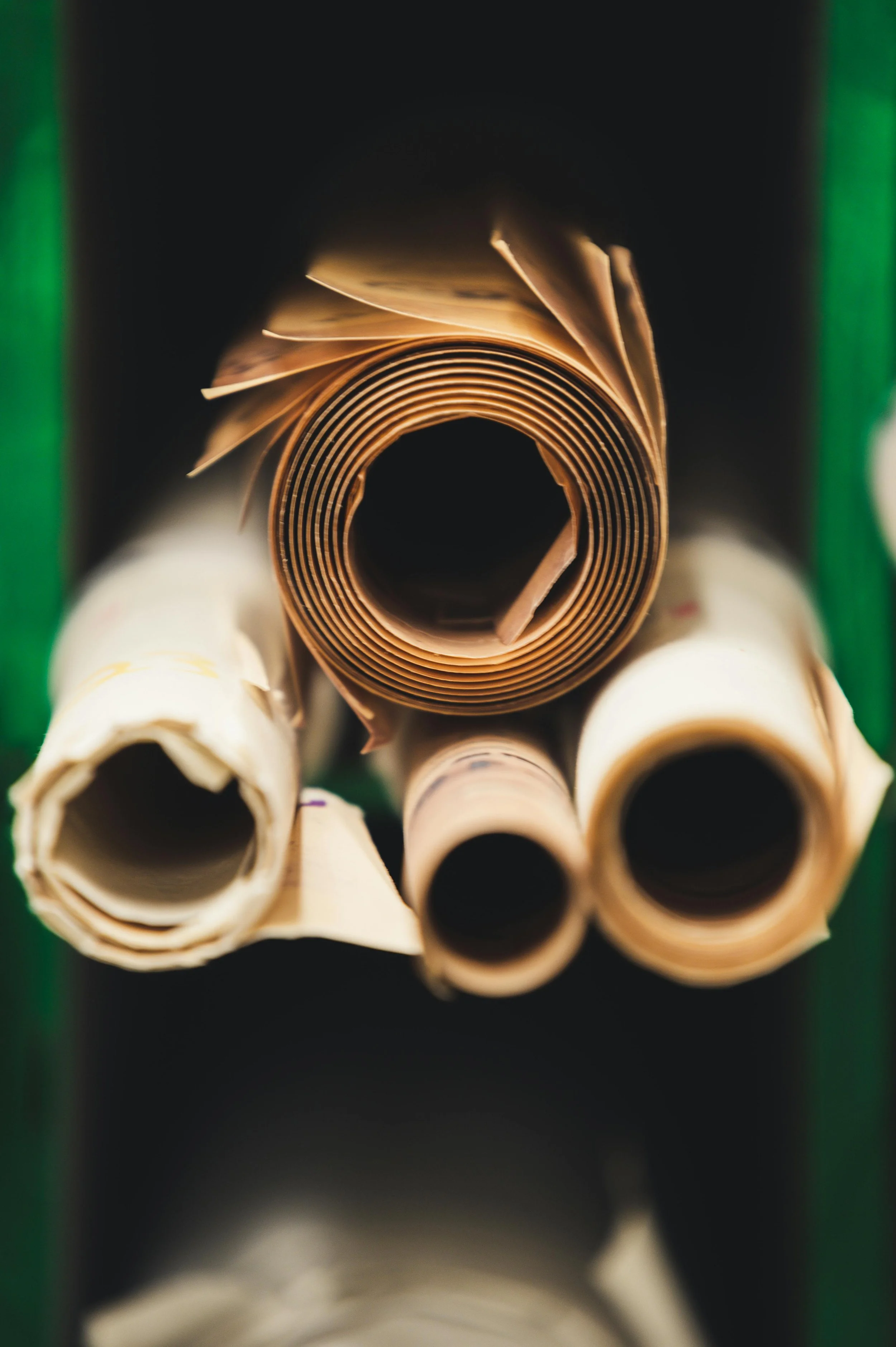 Close-up image of rolled paper tubes inside a cardboard box with a green edge.