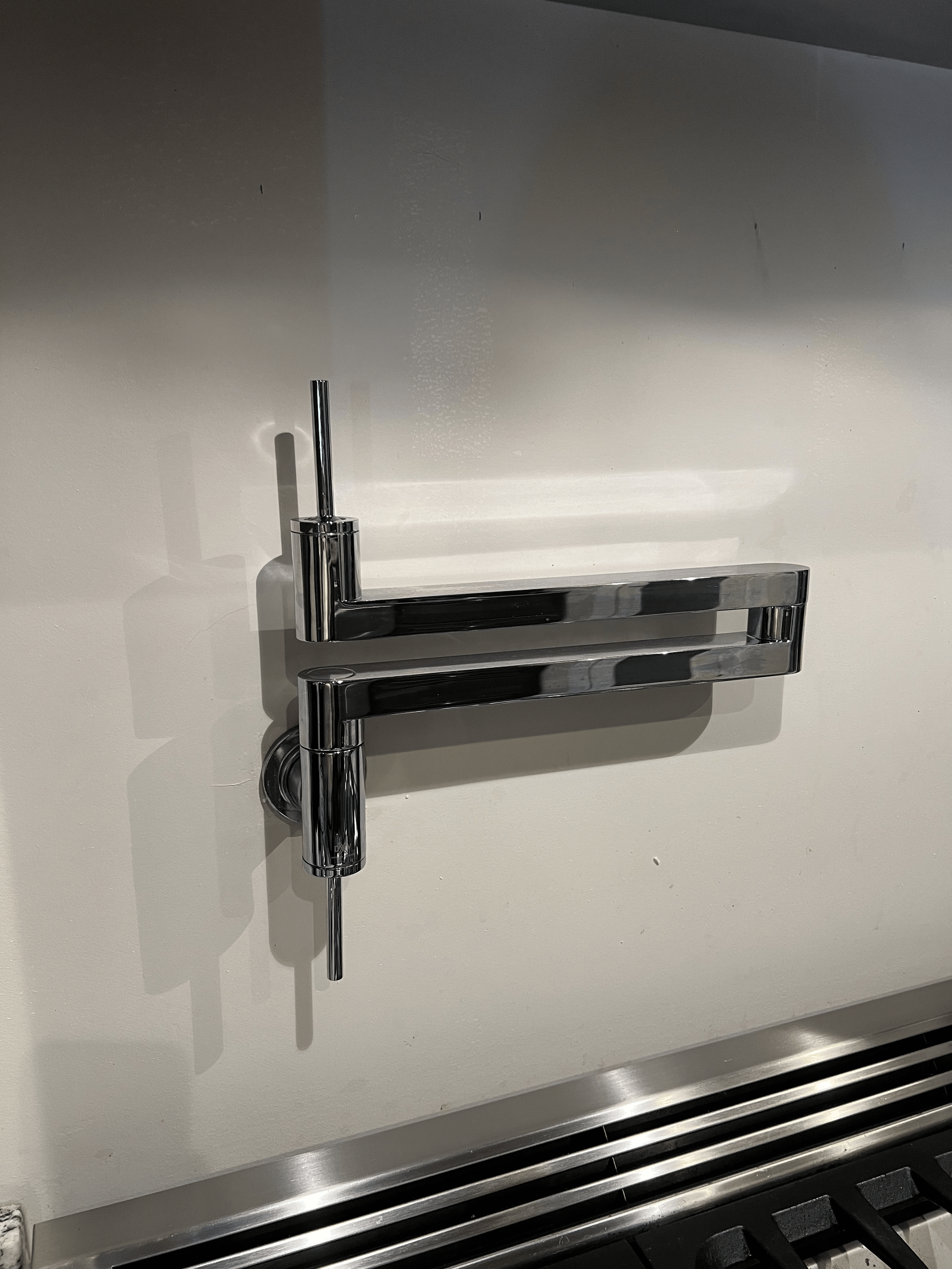 A modern stainless steel faucet mounted on a white countertop with a built-in drain, visible in the lower part of the image.