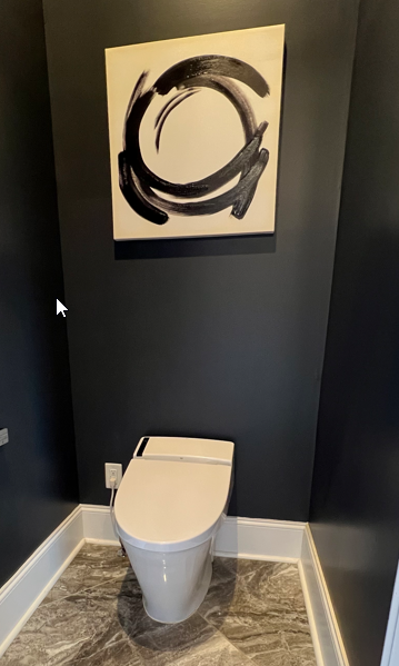 A modern bathroom with dark gray walls, a white toilet, and a large abstract black and white painting on the wall.