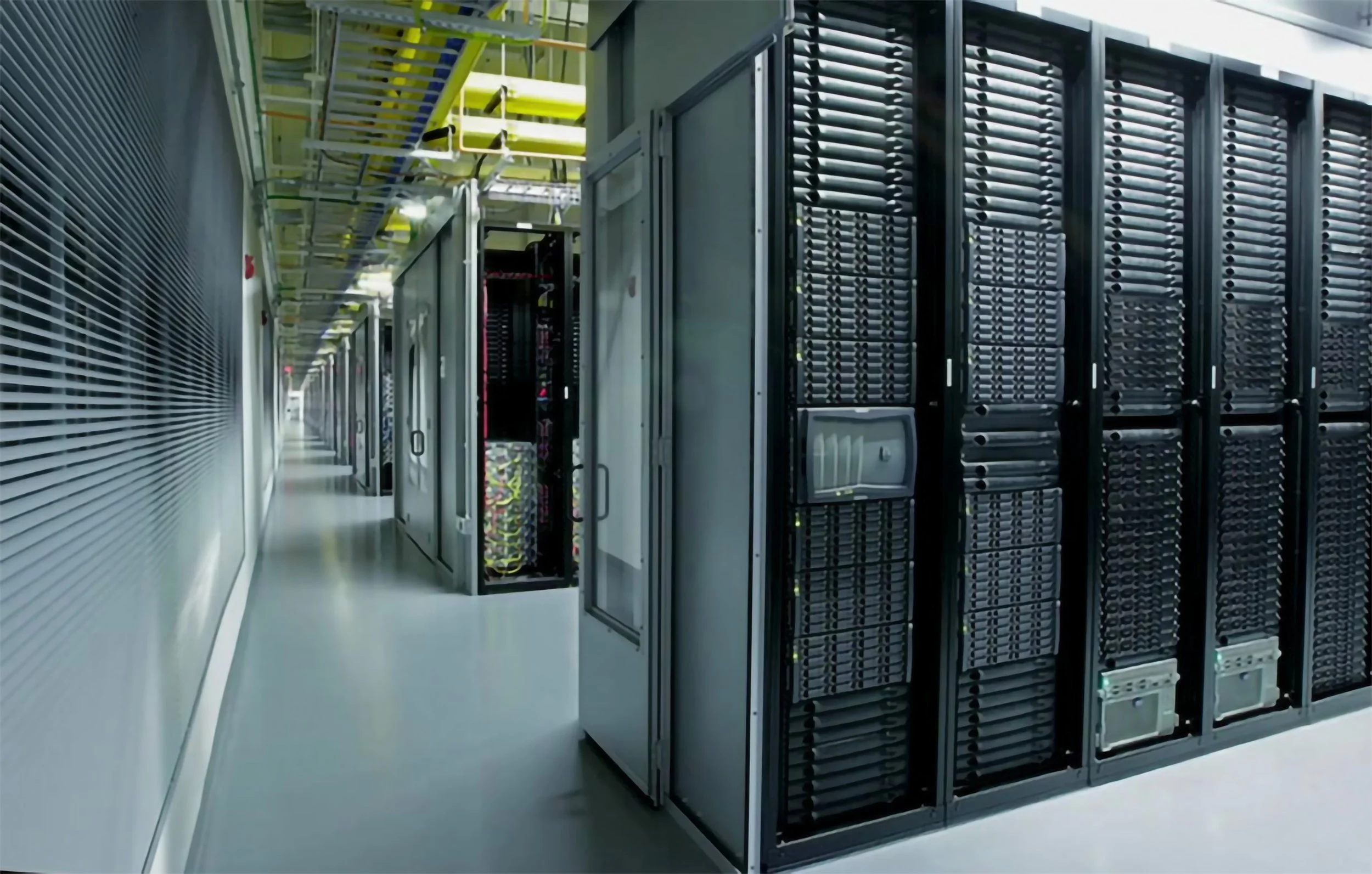 A data center with server racks and network equipment in a clean, well-lit corridor.