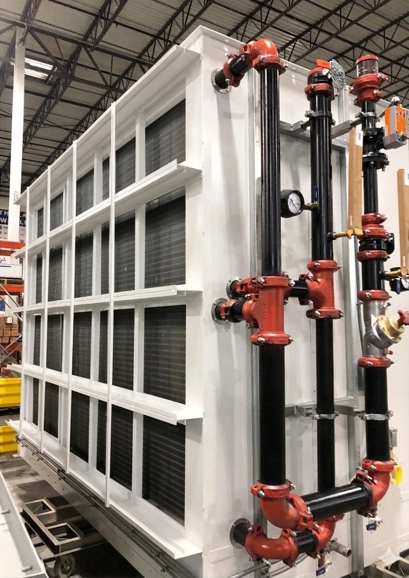 Industrial heat pump or chiller system with black pipes, red valves, gauges, and a white frame inside a data center