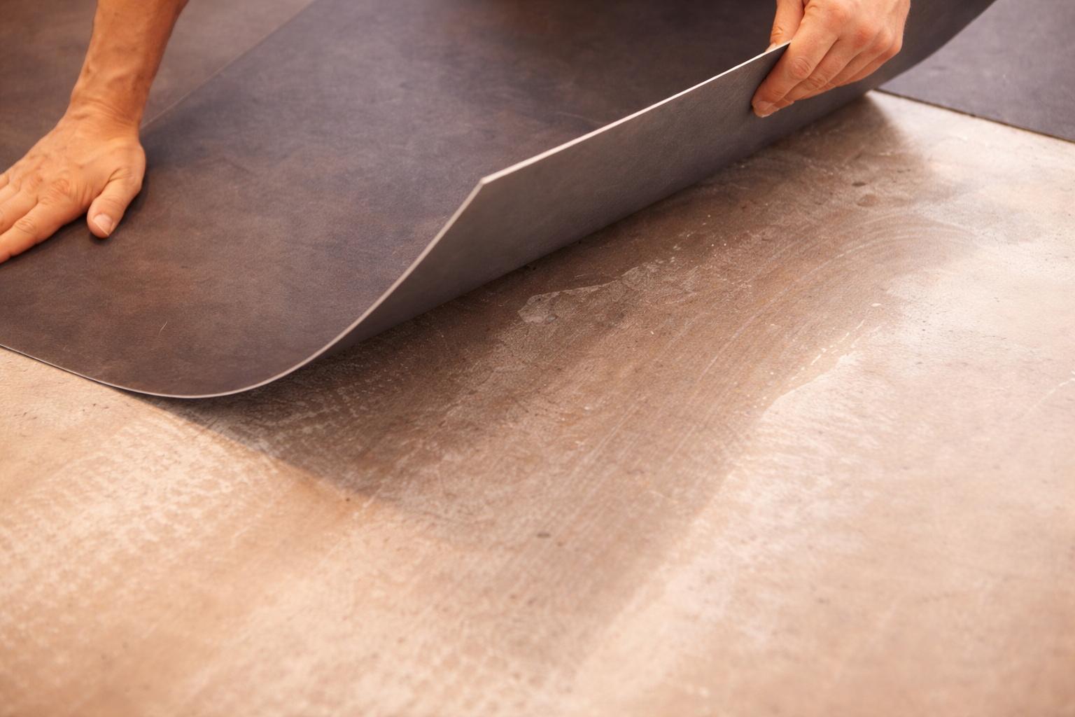 Person peeling back a layer of adhesive film from a ceramic tile surface.