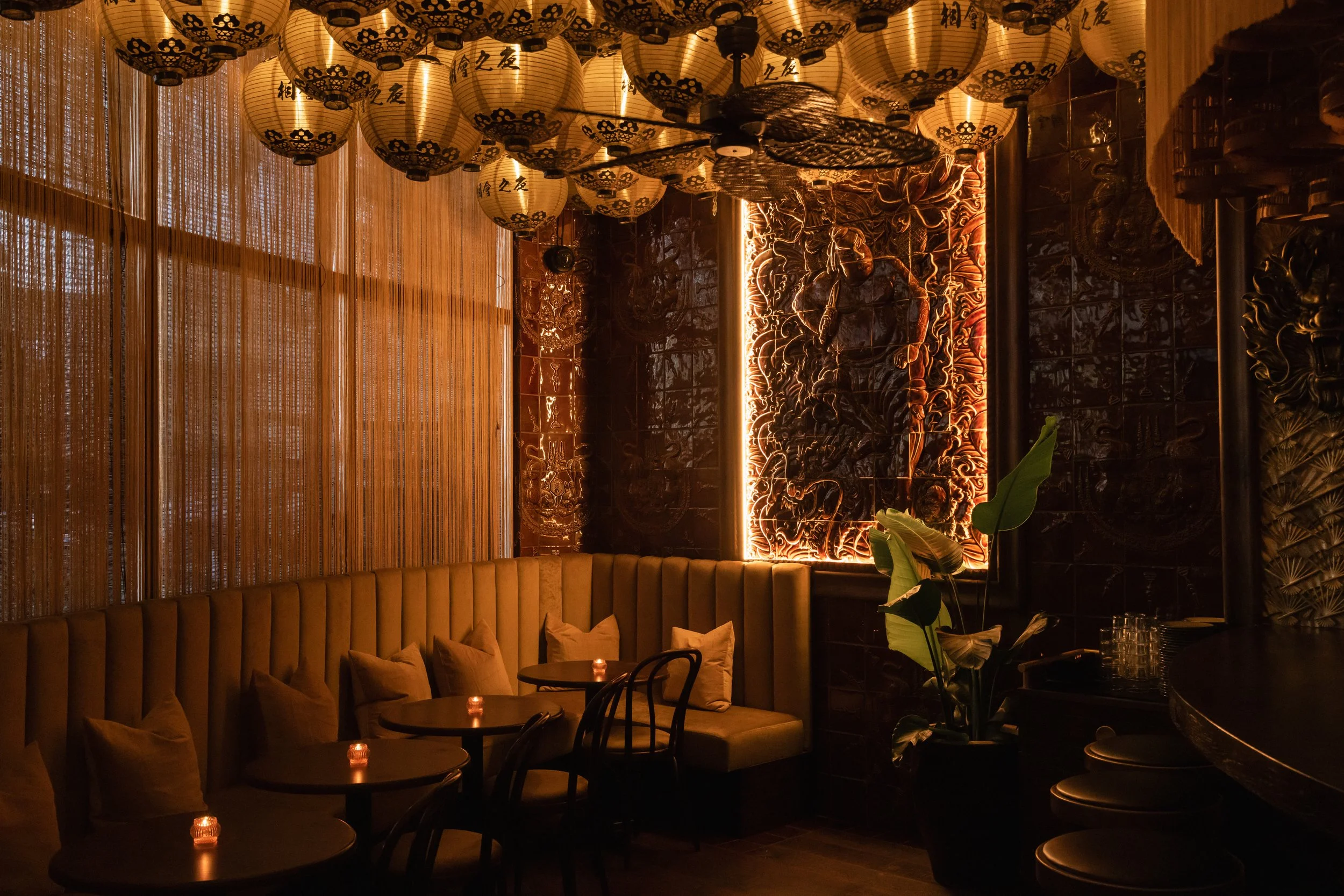 Corner of the restaurant is lined with cushy seats and an illuminated mural made up of ceramic brown tiles.