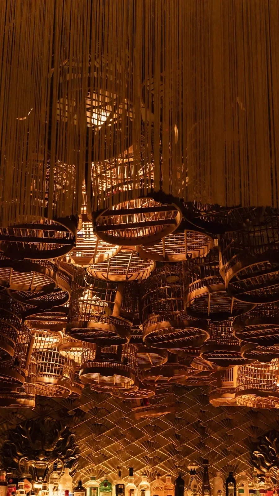 Wooden birdcages hang in the air, partially draped in a curtain of golden tassels.