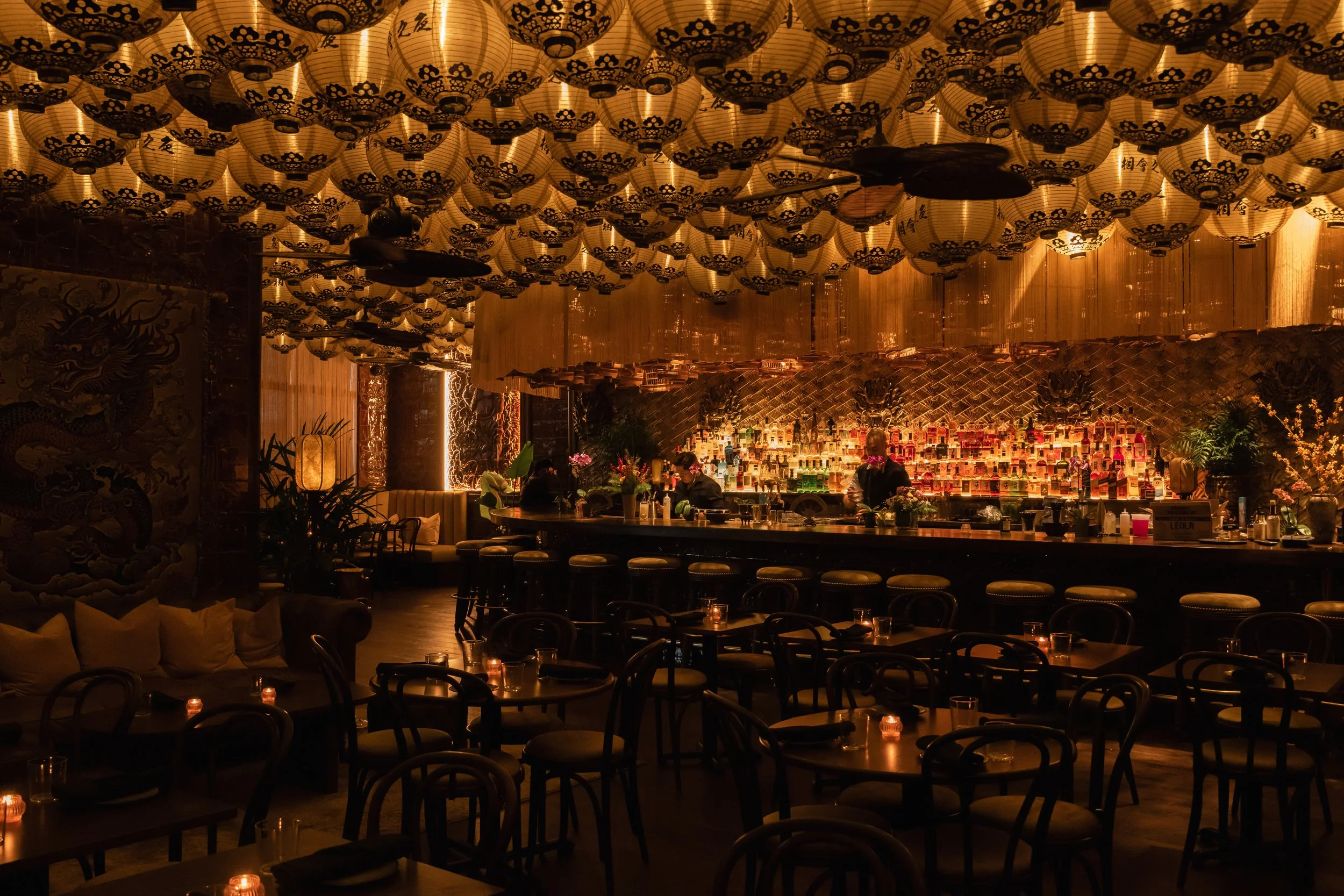 Restaurant interior with bar and tables, warmly lit by yellow Chinese lanterns