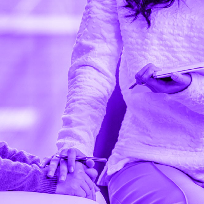 A person in a quilted jacket holding hands with another person, with a third person standing nearby holding a tablet.