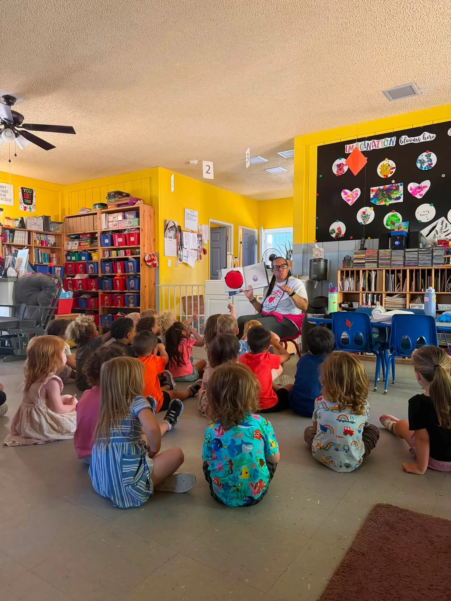 A group of preschool children and a teacher sitting together on the floor during circle time.