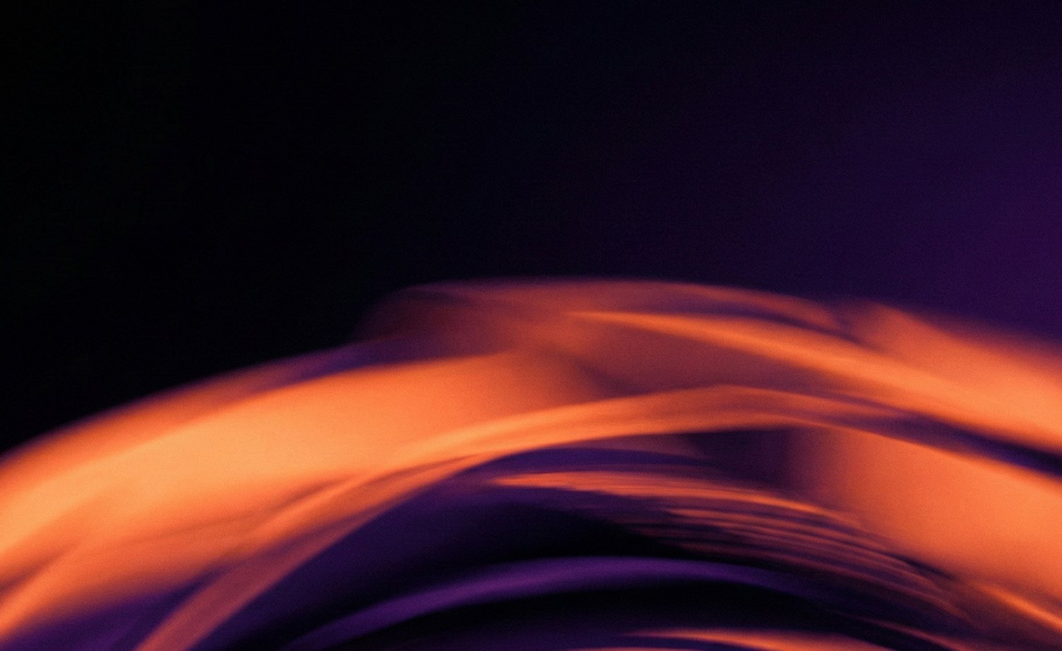 Líneas difusas y fluidas en tonos naranjas y morados sobre fondo oscuro.