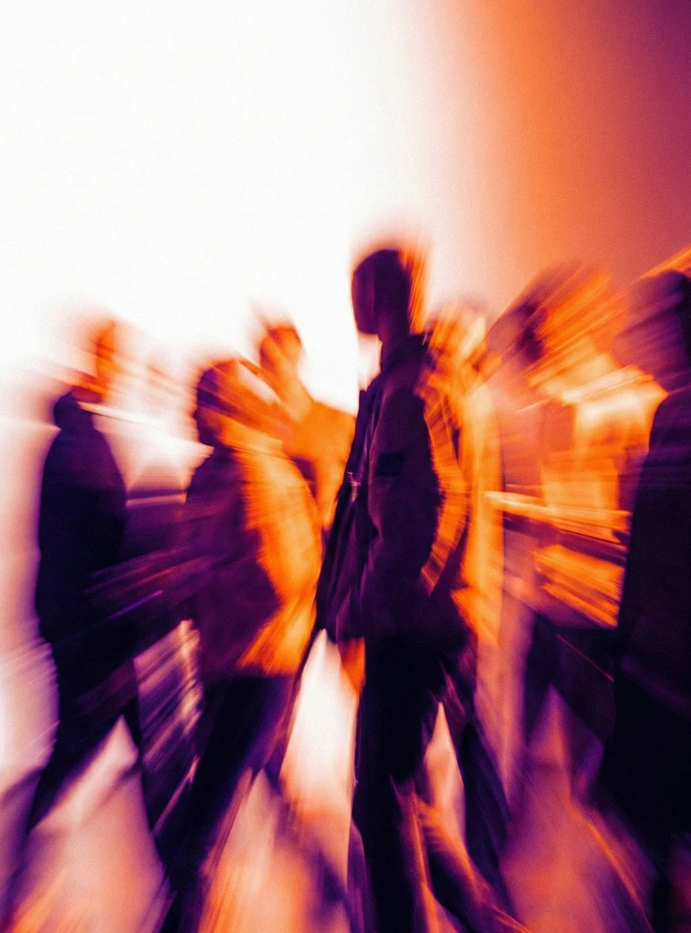 Grupo de personas en movimiento en un entorno con luz cálida, con efecto de desenfoque por movimiento.