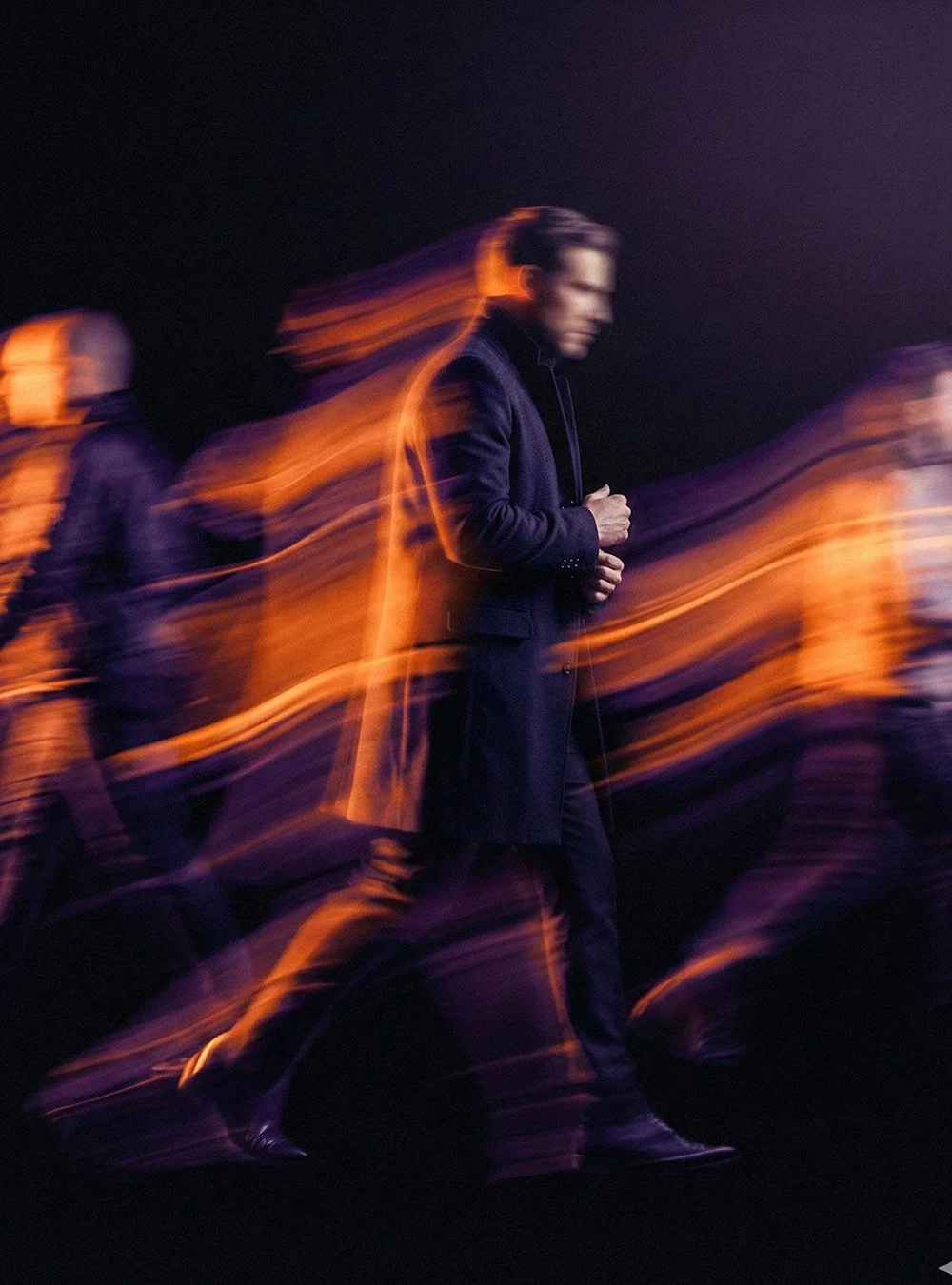 Hombre en un entorno oscuro caminando con movimiento y luz naranja resaltando movimiento.