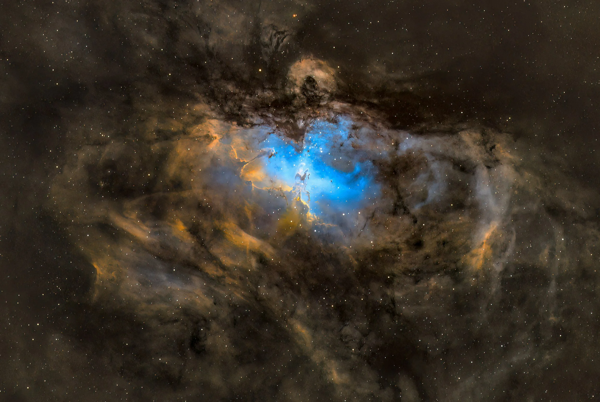 Immagine di una nebulosa nello spazio con colori blu, arancioni e neri, piena di stelle