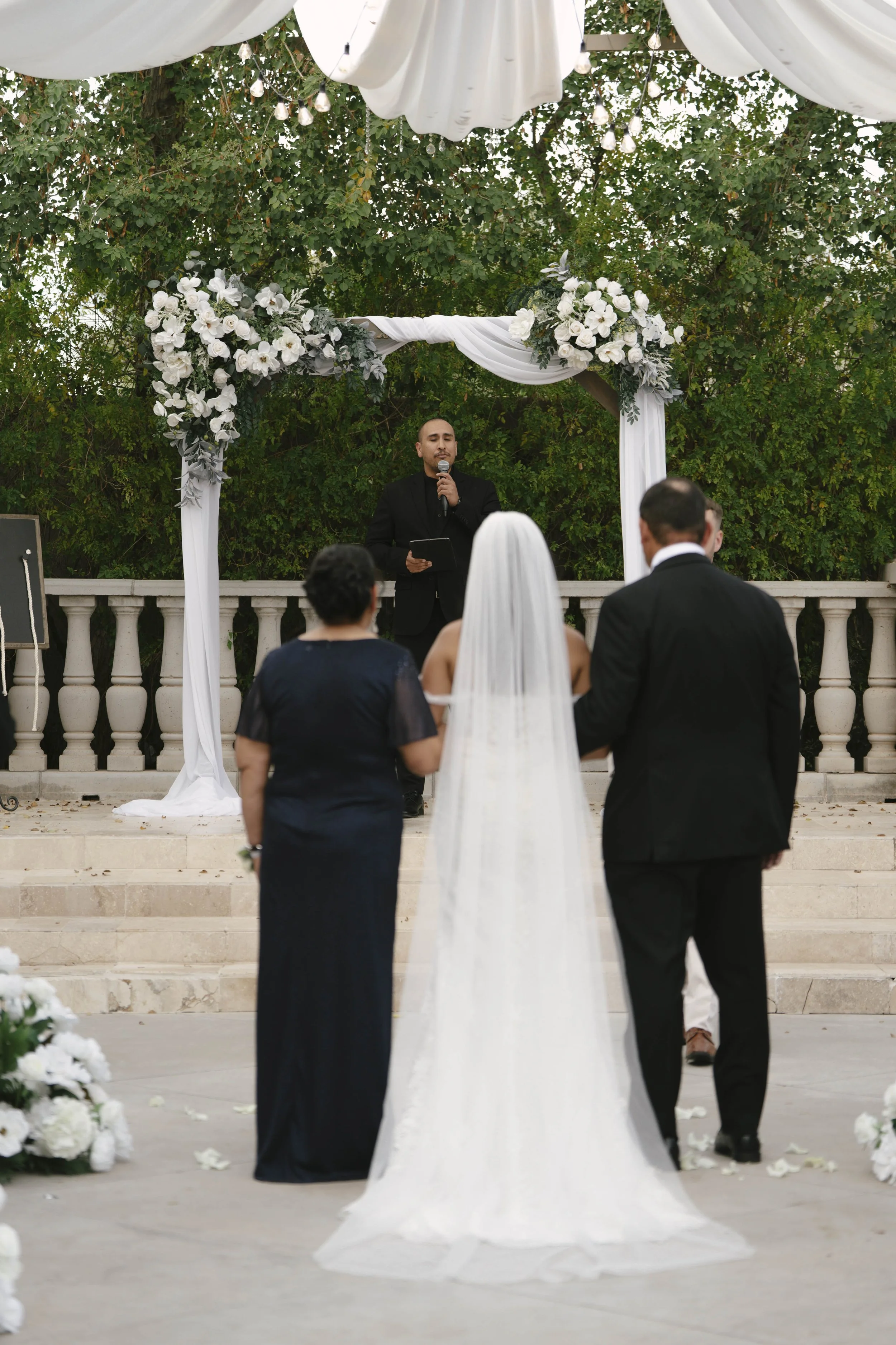 The wedding processional at Ashley Castle in Chandler, Arizona, was captured through hybrid film and digital photography, preserving the graceful entrances of the bridal party as they made their way through the romantic outdoor ceremony space surroun