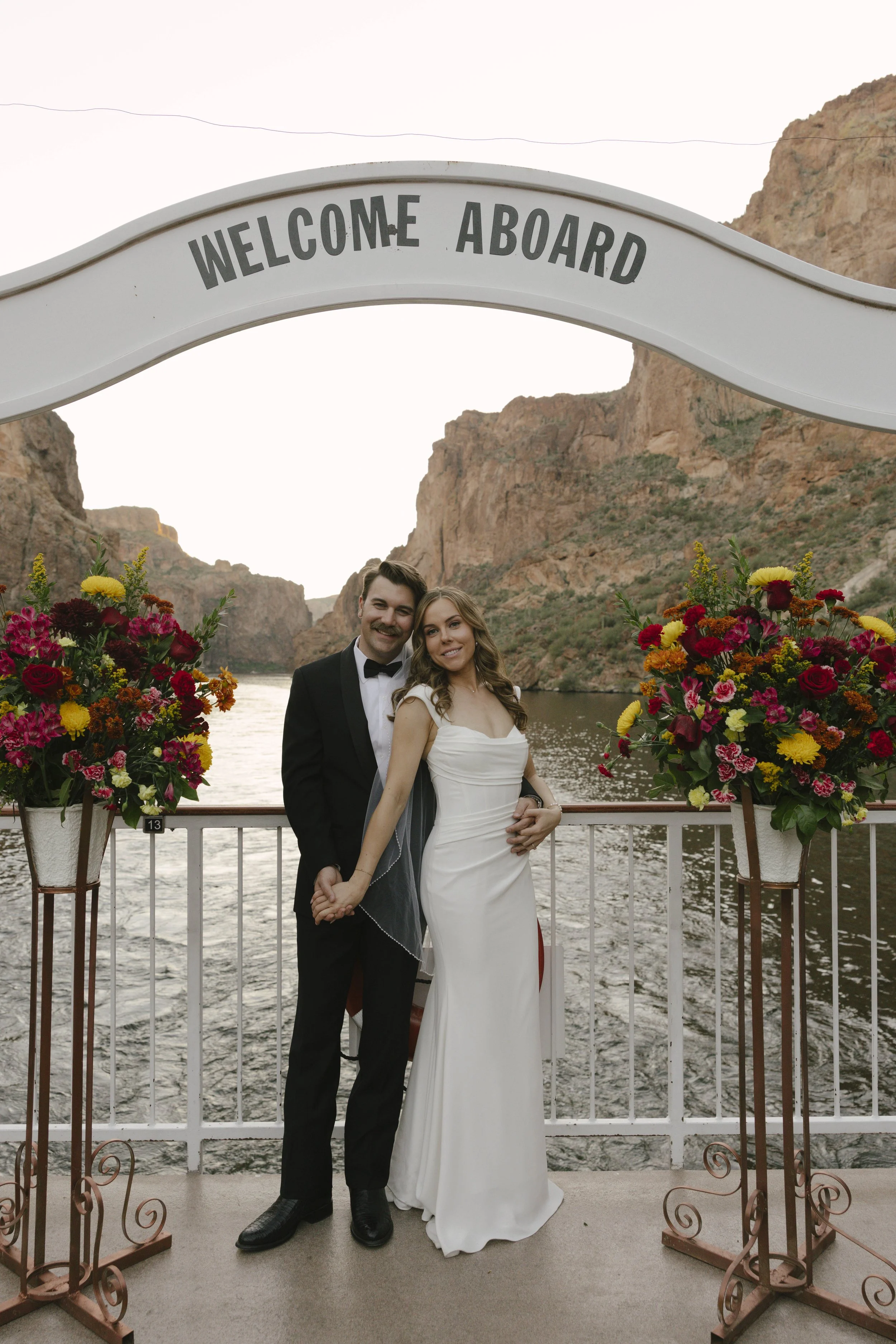 As the sun began to set over Canyon Lake, the couple stepped onto the deck of the Dolly Steamboat for golden hour portraits. With warm Arizona light reflecting off the water and desert mountains surrounding them, these quiet moments captured the beau
