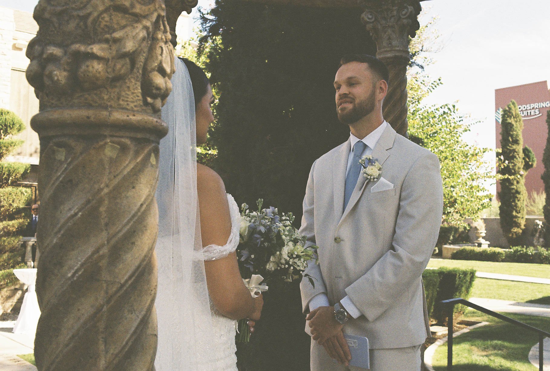 The bride and groom’s first look at Ashley Castle in Chandler, Arizona, unfolded in the venue’s romantic garden gazebo, where hybrid film and digital photography captured their emotional private reveal with timeless elegance, natural light, and intim