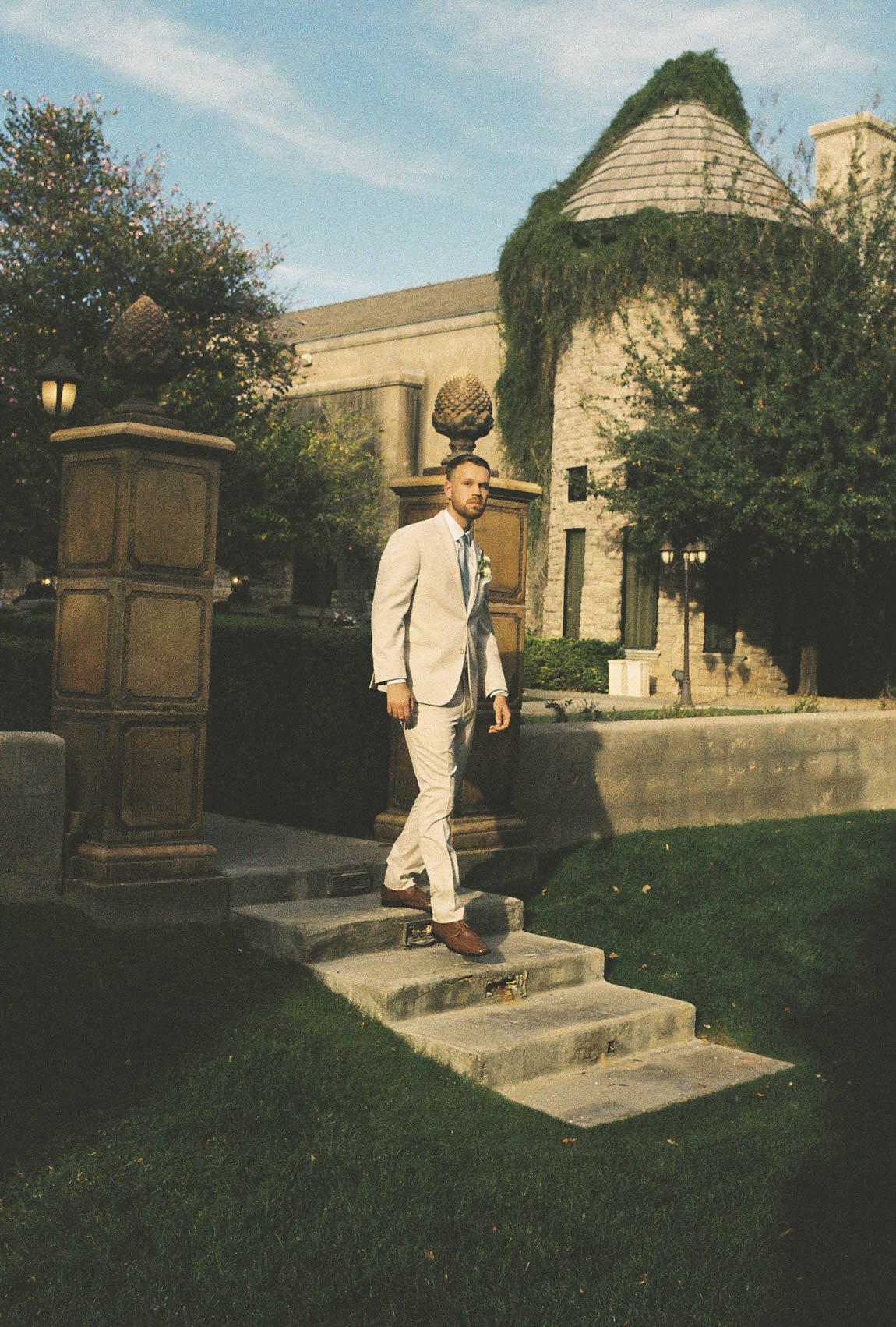The groom’s portraits at Ashley Castle in Chandler, Arizona, were captured through hybrid film and digital photography, highlighting timeless style, refined details, and elegant garden backdrops that complement the venue’s romantic castle setting.