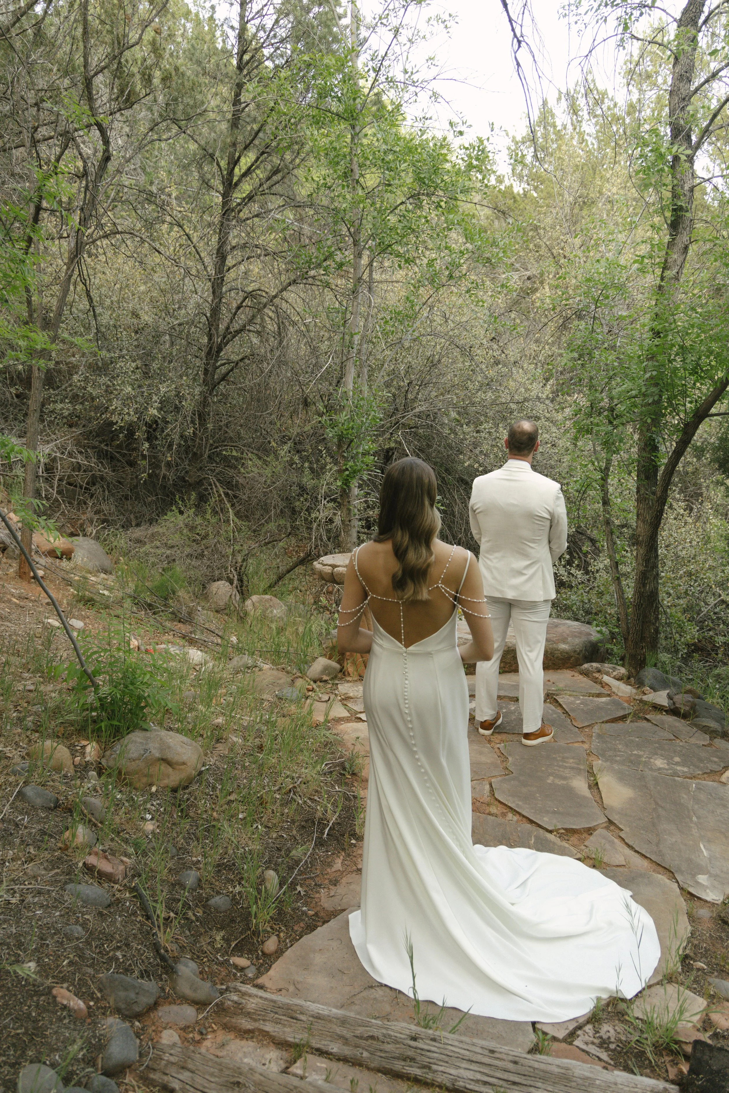 Chelsea and Travis shared an intimate first look surrounded by the natural beauty of Sedona before exchanging vows during their private Arizona elopement ceremony. Set along a peaceful garden path, these heartfelt moments marked the beginning of thei