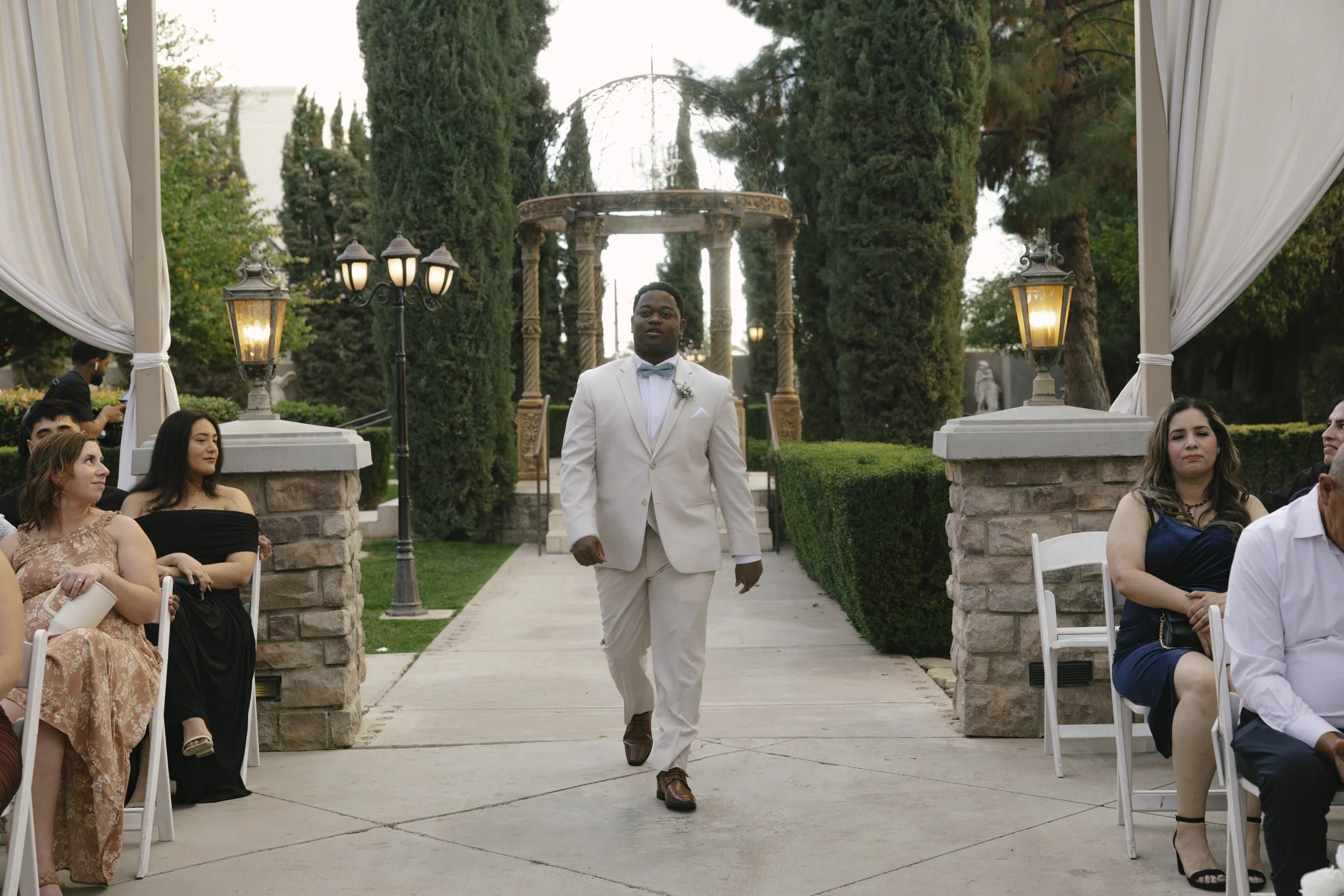 The wedding processional at Ashley Castle in Chandler, Arizona, was captured through hybrid film and digital photography, preserving the graceful entrances of the bridal party as they made their way through the romantic outdoor ceremony space surroun