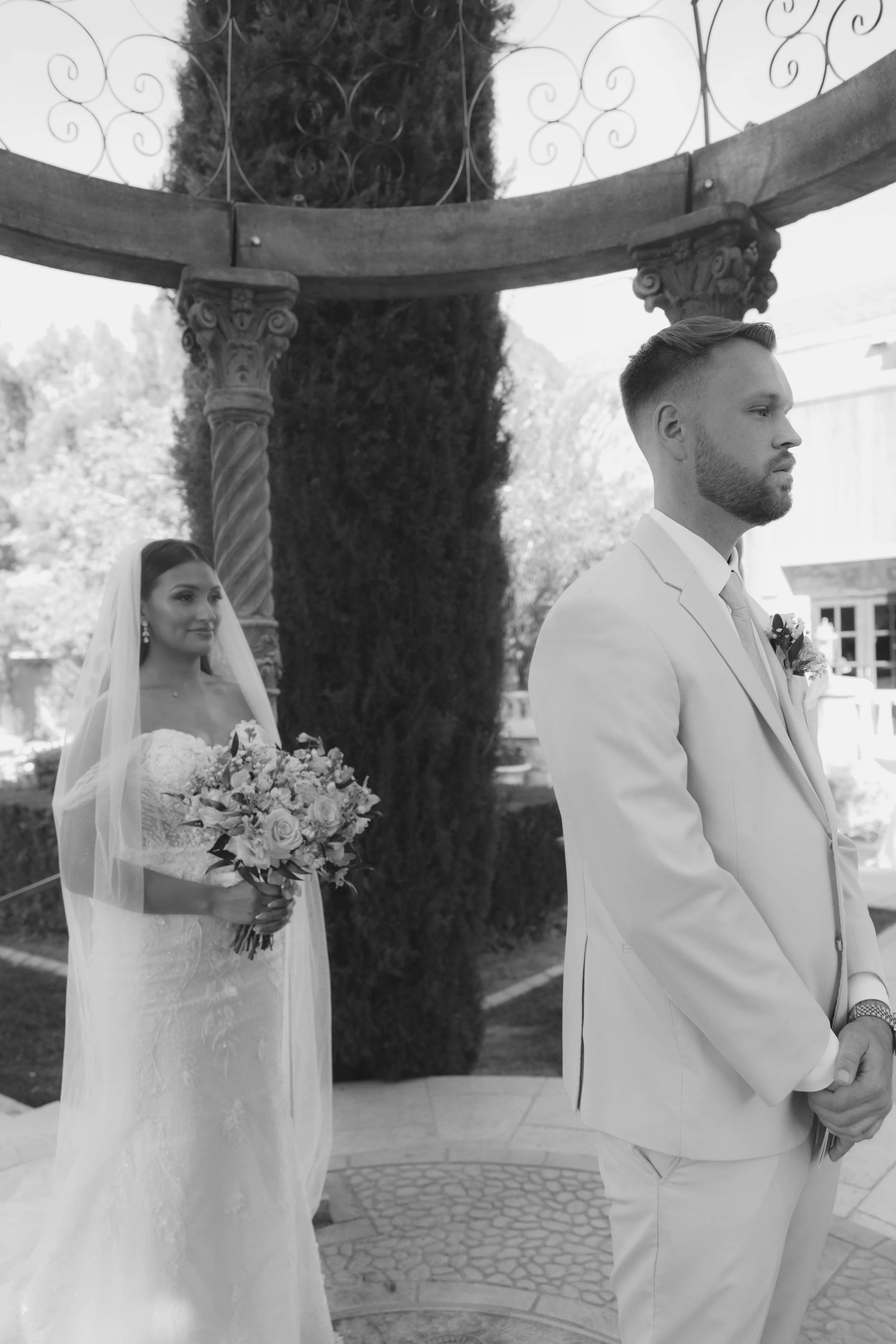 The bride and groom’s first look at Ashley Castle in Chandler, Arizona, unfolded in the venue’s romantic garden gazebo, where hybrid film and digital photography captured their emotional private reveal with timeless elegance, natural light, and intim