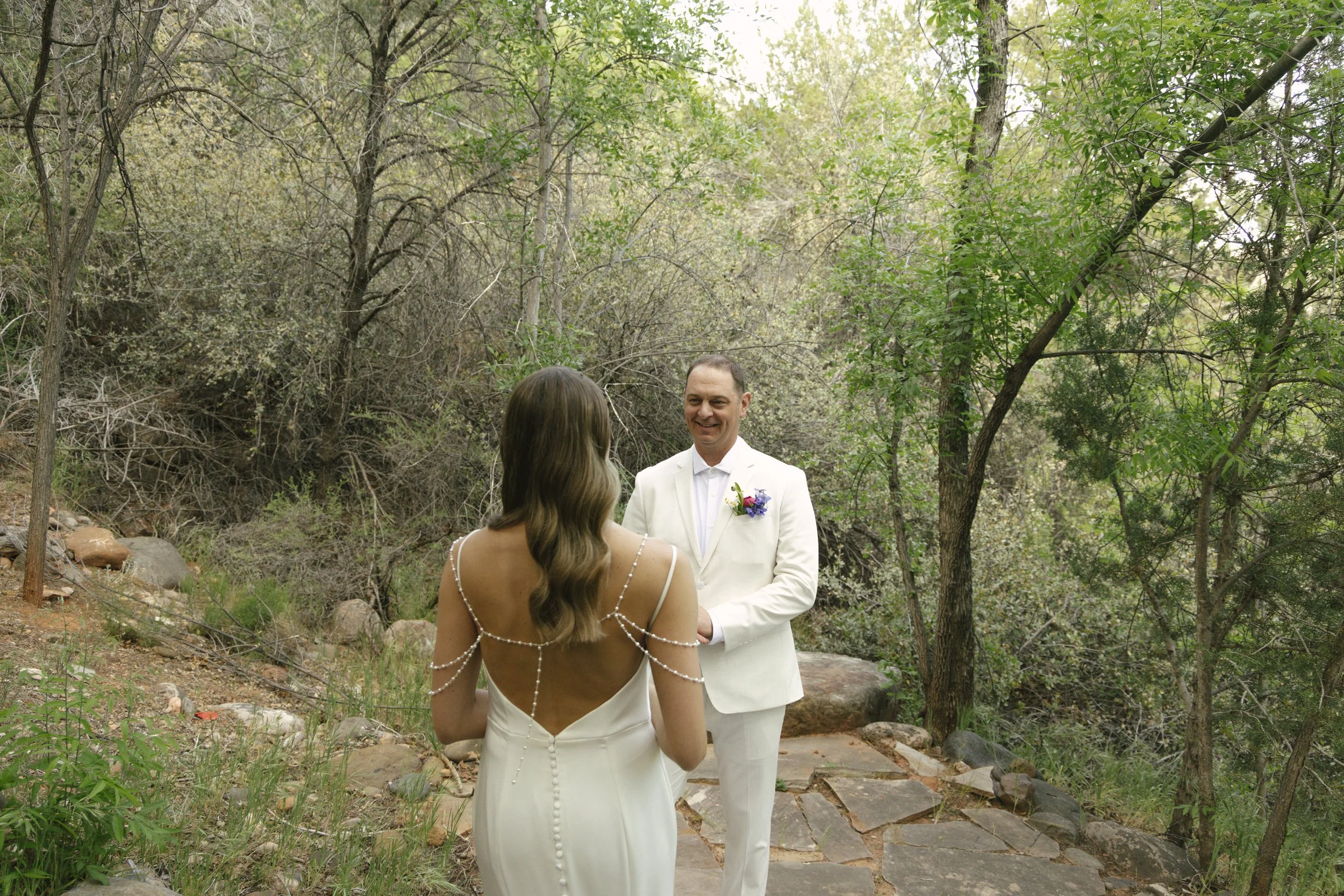 Chelsea and Travis shared an intimate first look surrounded by the natural beauty of Sedona before exchanging vows during their private Arizona elopement ceremony. Set along a peaceful garden path, these heartfelt moments marked the beginning of thei