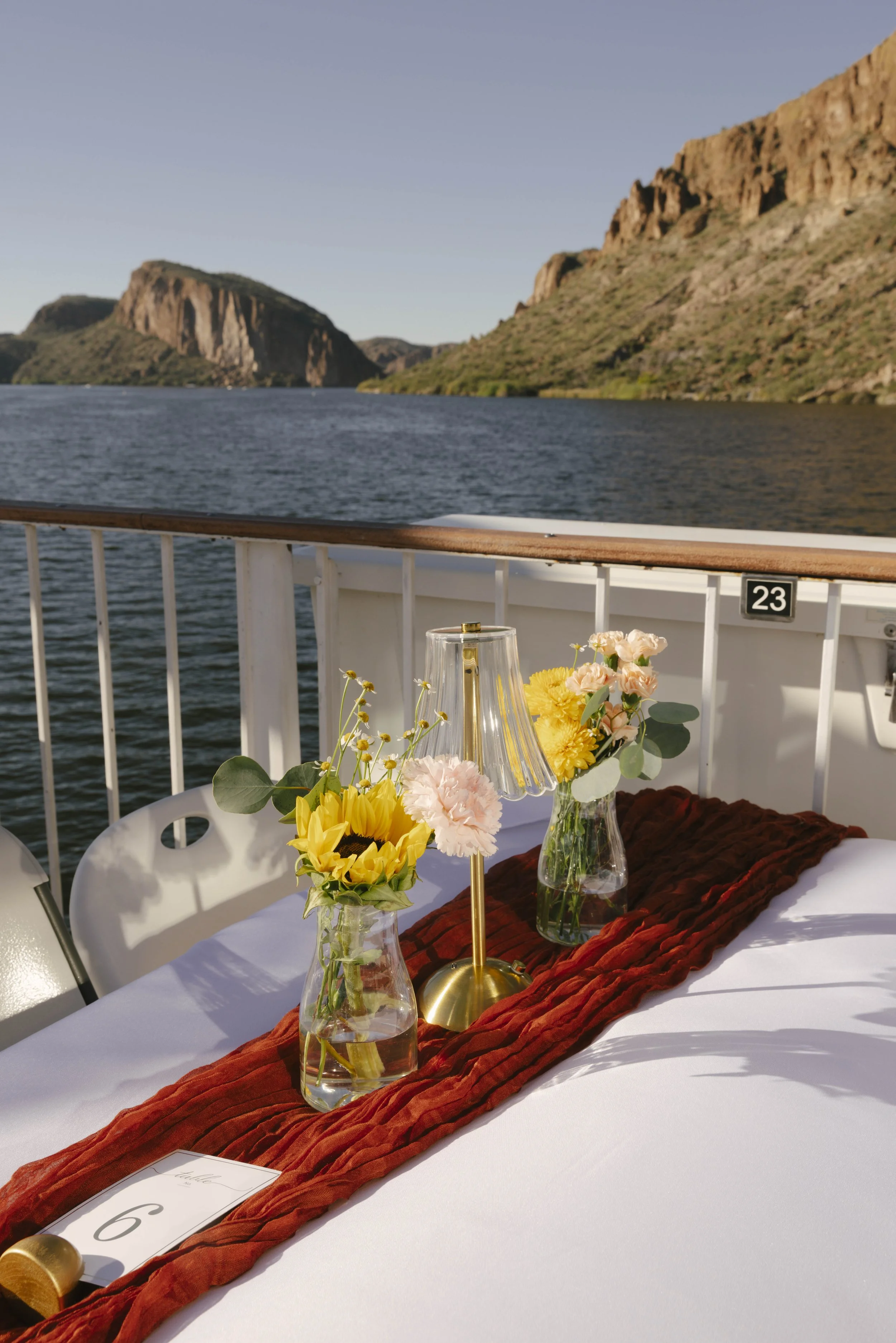 As the Dolly Steamboat cruised through Canyon Lake, guests enjoyed an intimate reception surrounded by Arizona’s desert mountains and open water. The tables were beautifully set with warm tones, fresh florals, and thoughtful details that complemented