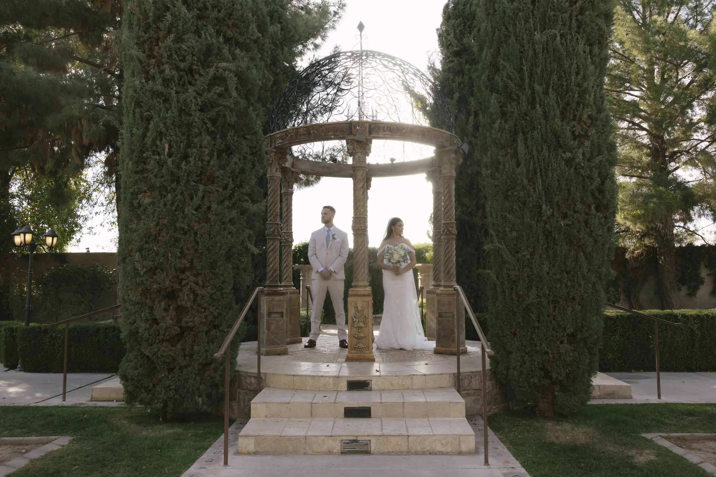 The bride and groom’s first look at Ashley Castle in Chandler, Arizona, unfolded in the venue’s romantic garden gazebo, where hybrid film and digital photography captured their emotional private reveal with timeless elegance, natural light, and intim
