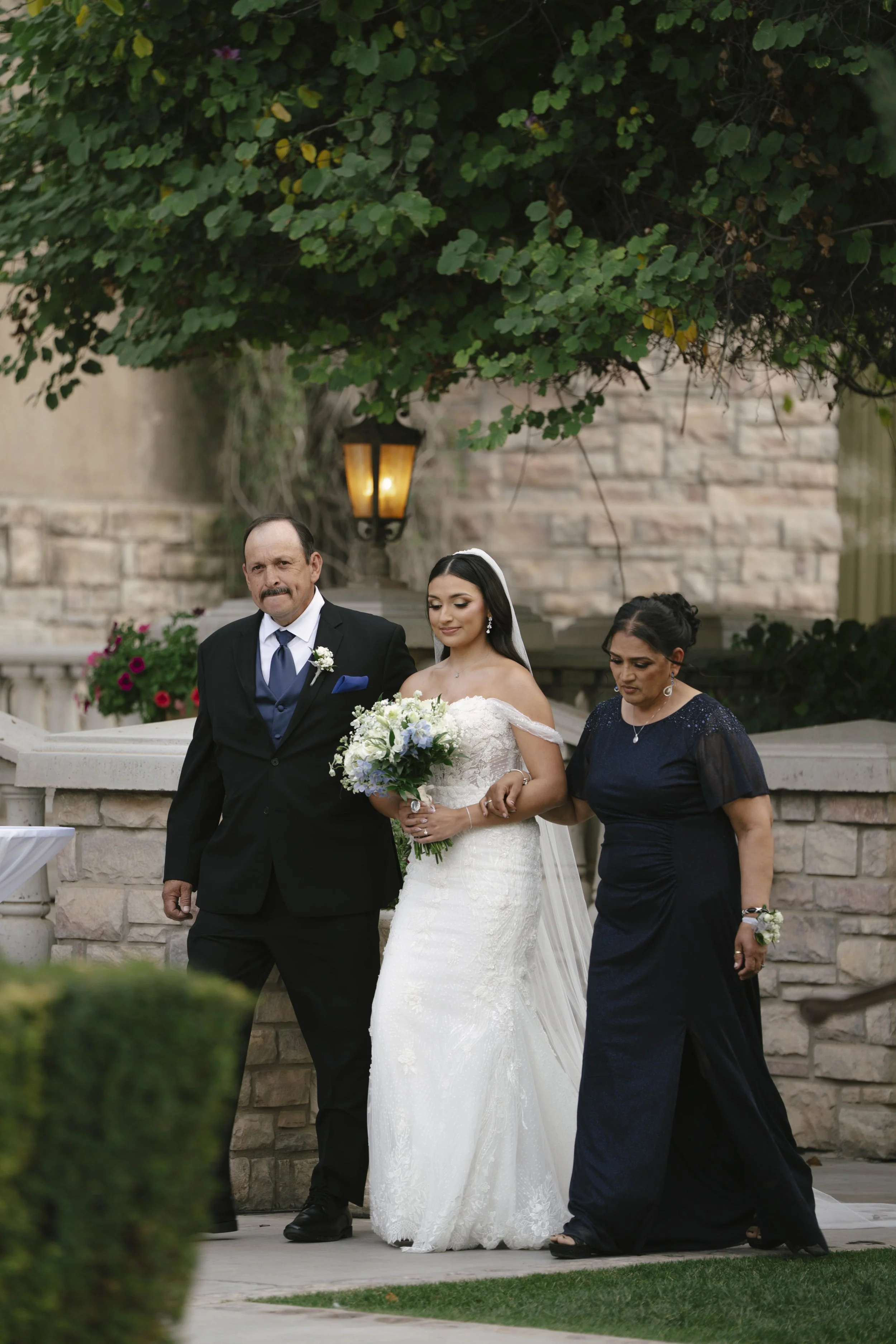The wedding processional at Ashley Castle in Chandler, Arizona, was captured through hybrid film and digital photography, preserving the graceful entrances of the bridal party as they made their way through the romantic outdoor ceremony space surroun