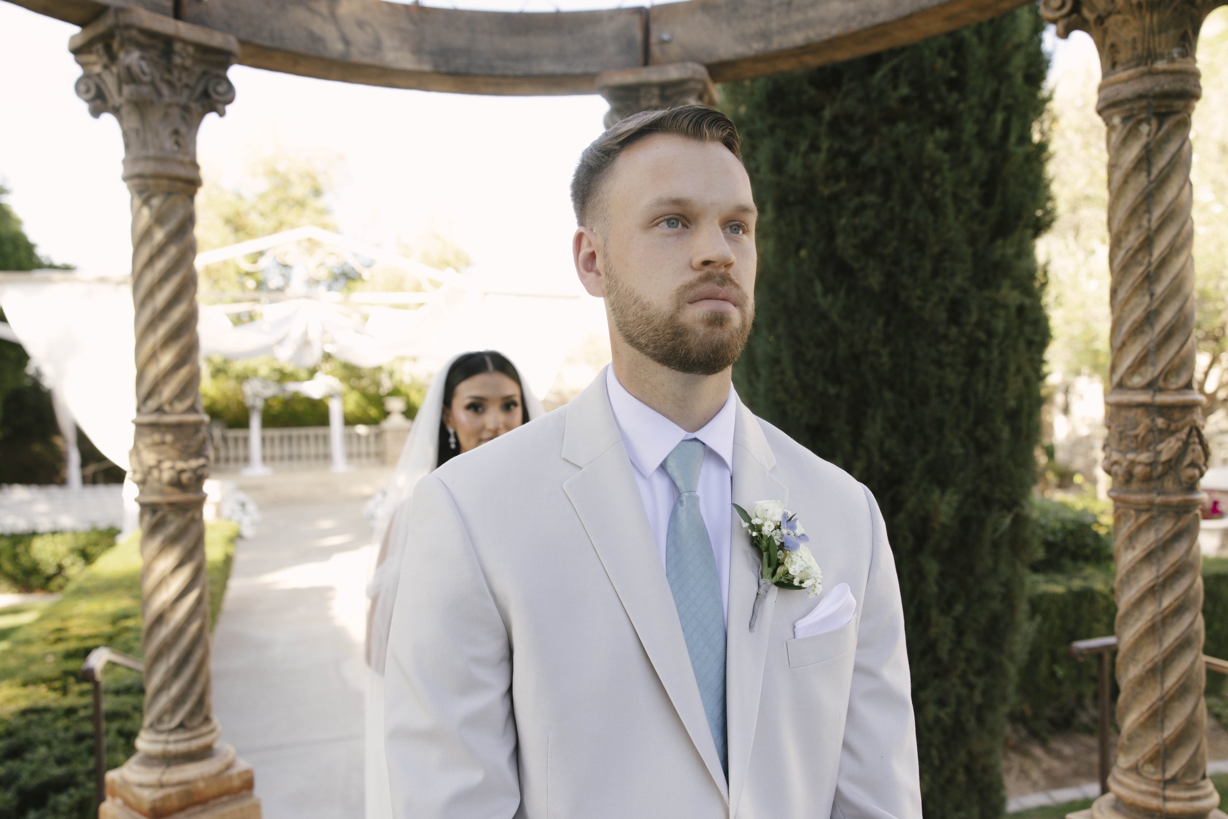 The bride and groom’s first look at Ashley Castle in Chandler, Arizona, unfolded in the venue’s romantic garden gazebo, where hybrid film and digital photography captured their emotional private reveal with timeless elegance, natural light, and intim