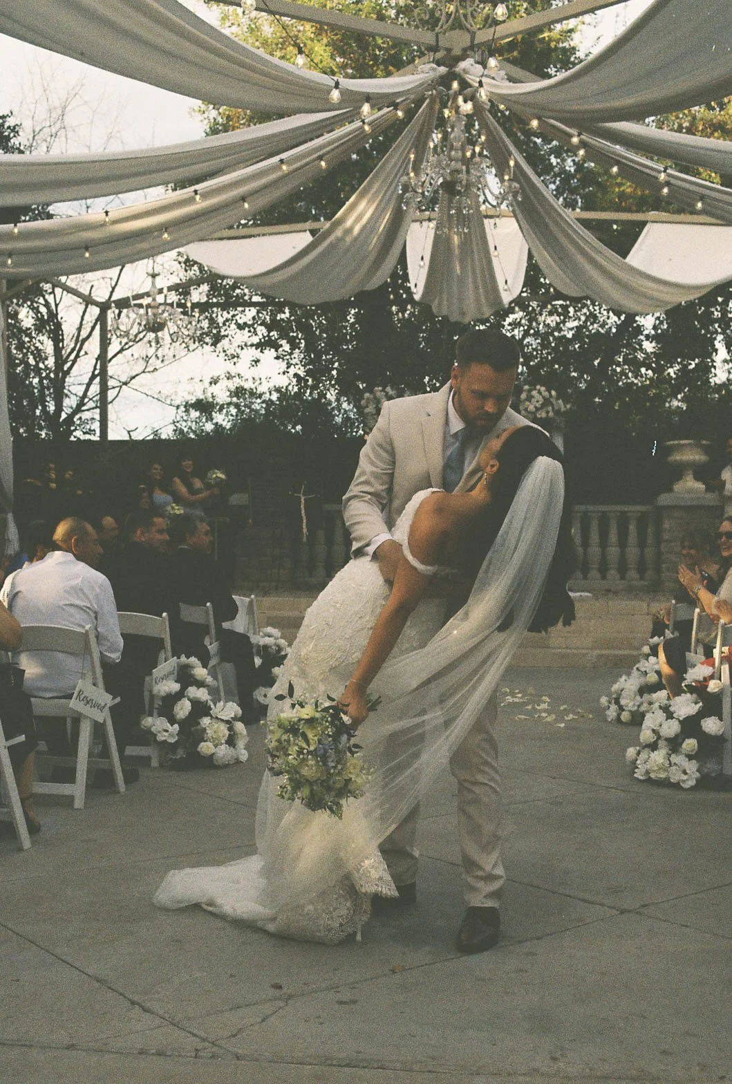 The bride and groom’s ceremony at Ashley Castle in Chandler, Arizona, was beautifully documented through hybrid film and digital photography, capturing their vows, ring exchange, and heartfelt moments beneath a romantic floral altar in the castle’s e