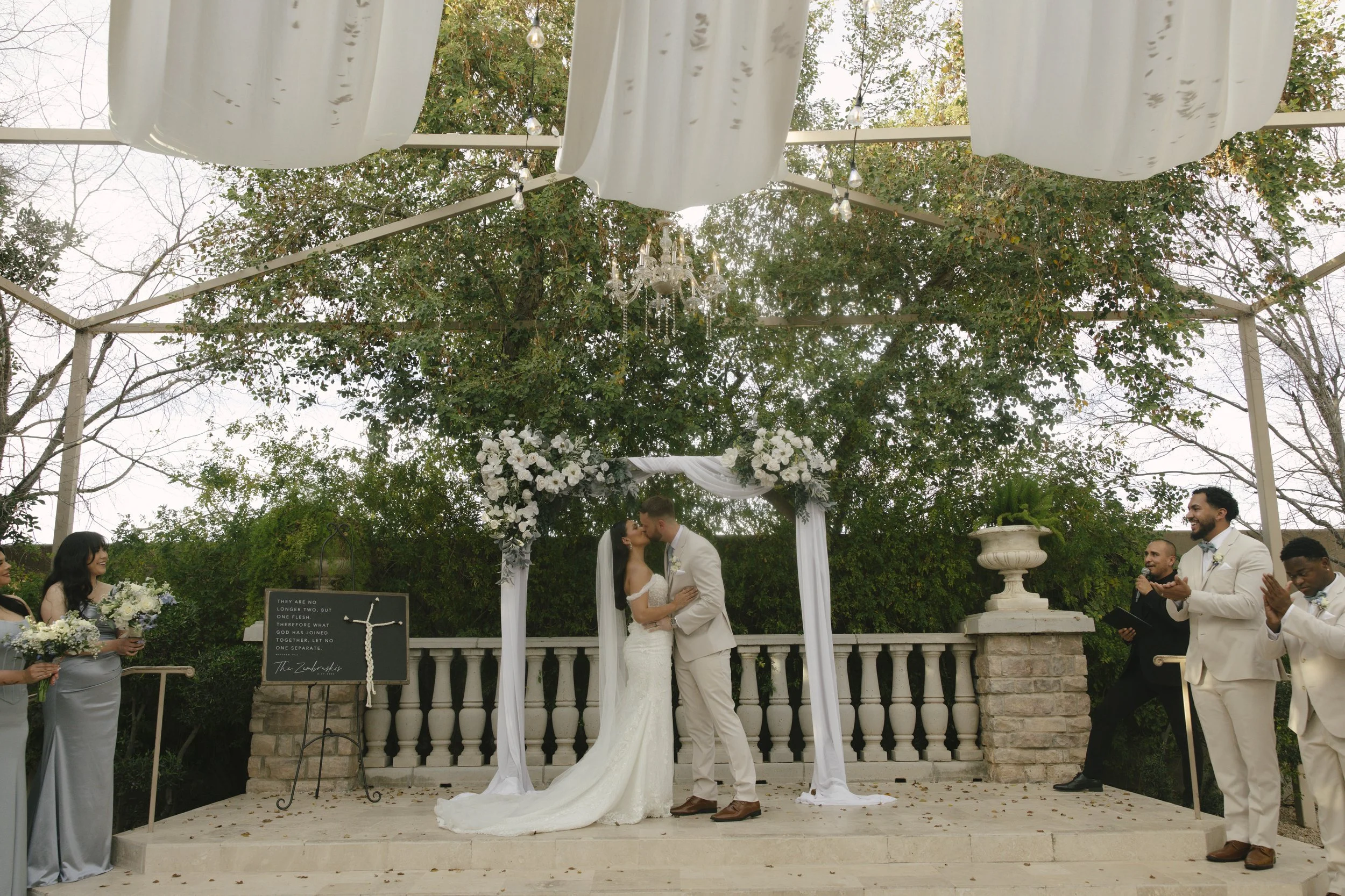 The bride and groom’s ceremony at Ashley Castle in Chandler, Arizona, was beautifully documented through hybrid film and digital photography, capturing their vows, ring exchange, and heartfelt moments beneath a romantic floral altar in the castle’s e
