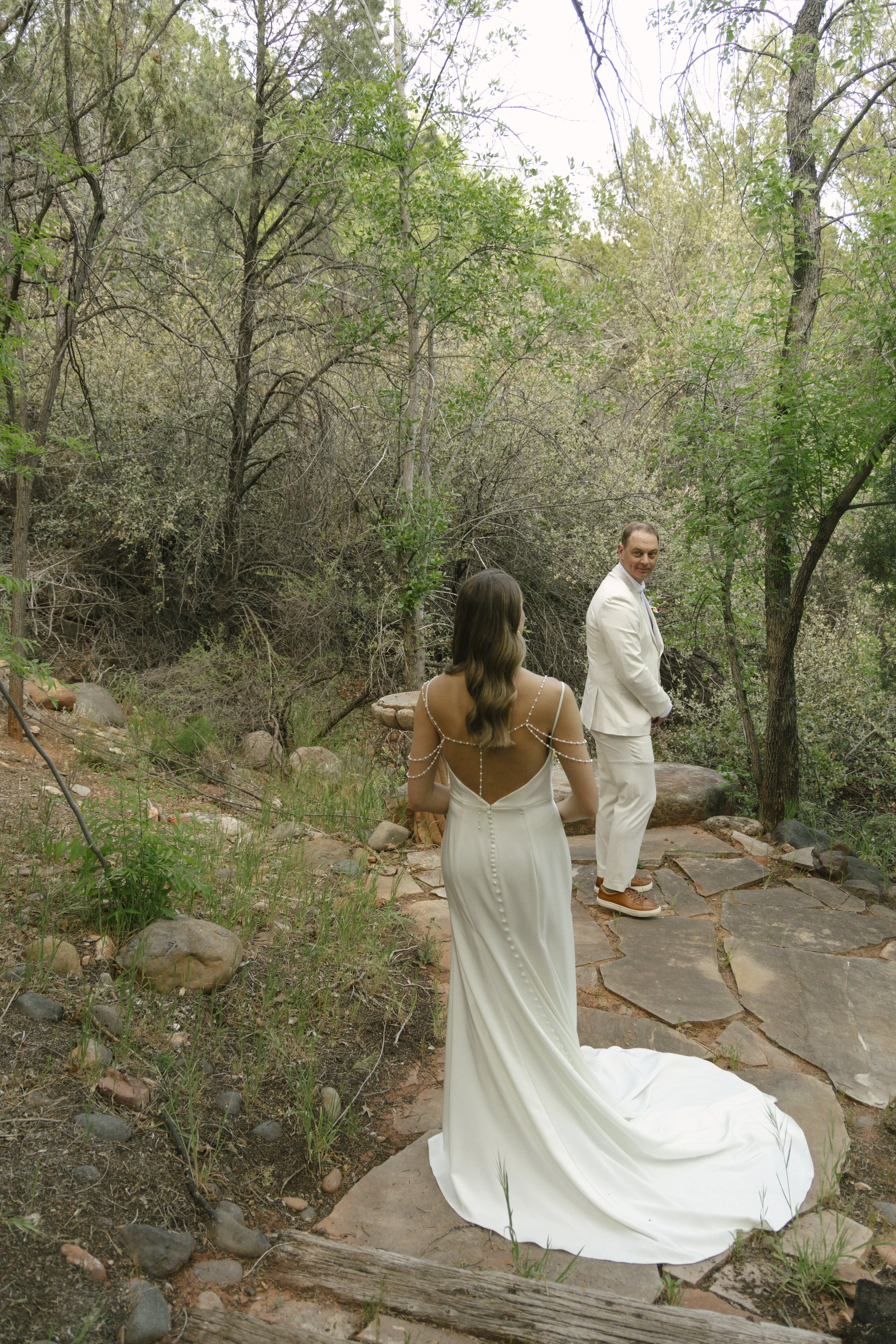 Chelsea and Travis shared an intimate first look surrounded by the natural beauty of Sedona before exchanging vows during their private Arizona elopement ceremony. Set along a peaceful garden path, these heartfelt moments marked the beginning of thei