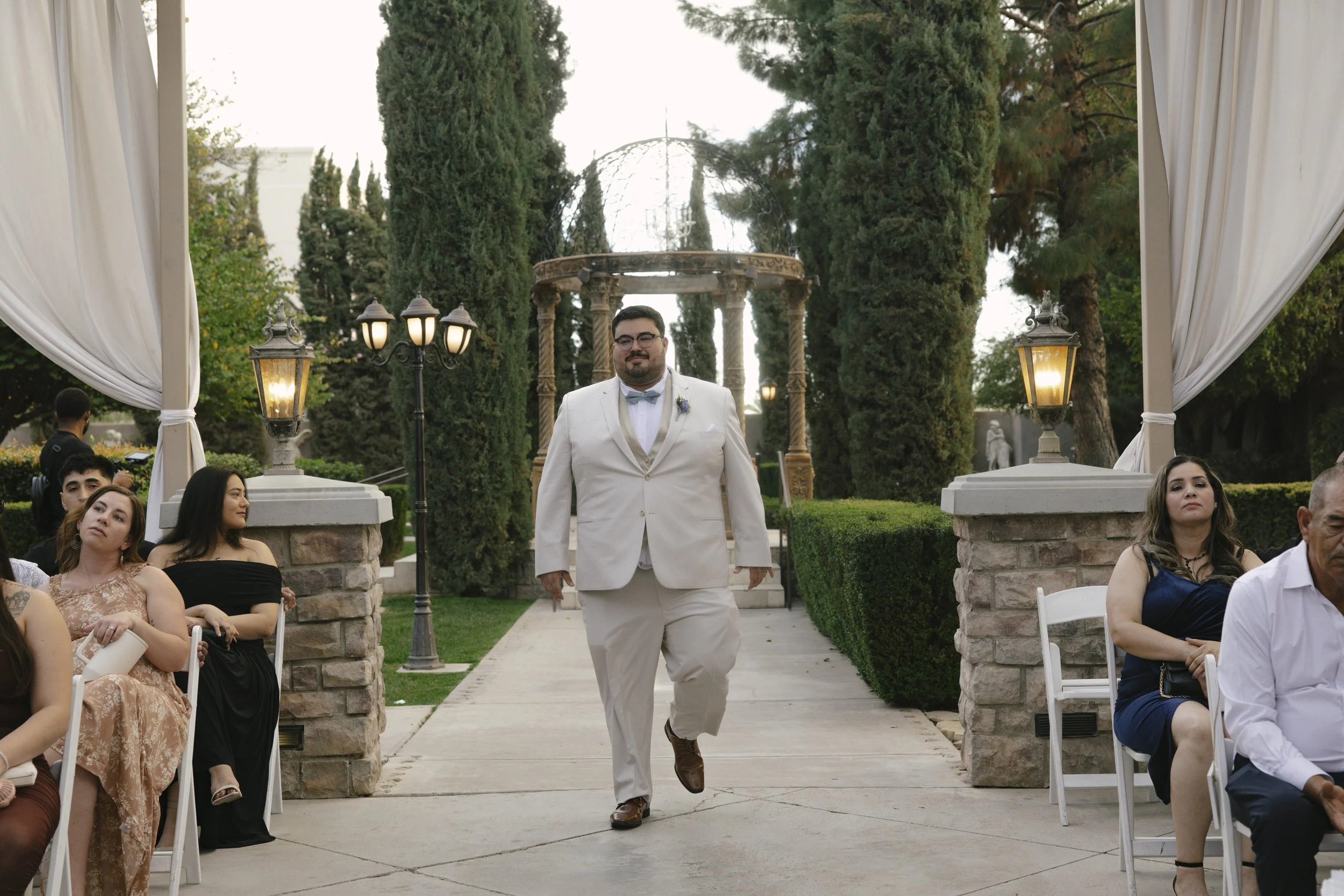The wedding processional at Ashley Castle in Chandler, Arizona, was captured through hybrid film and digital photography, preserving the graceful entrances of the bridal party as they made their way through the romantic outdoor ceremony space surroun