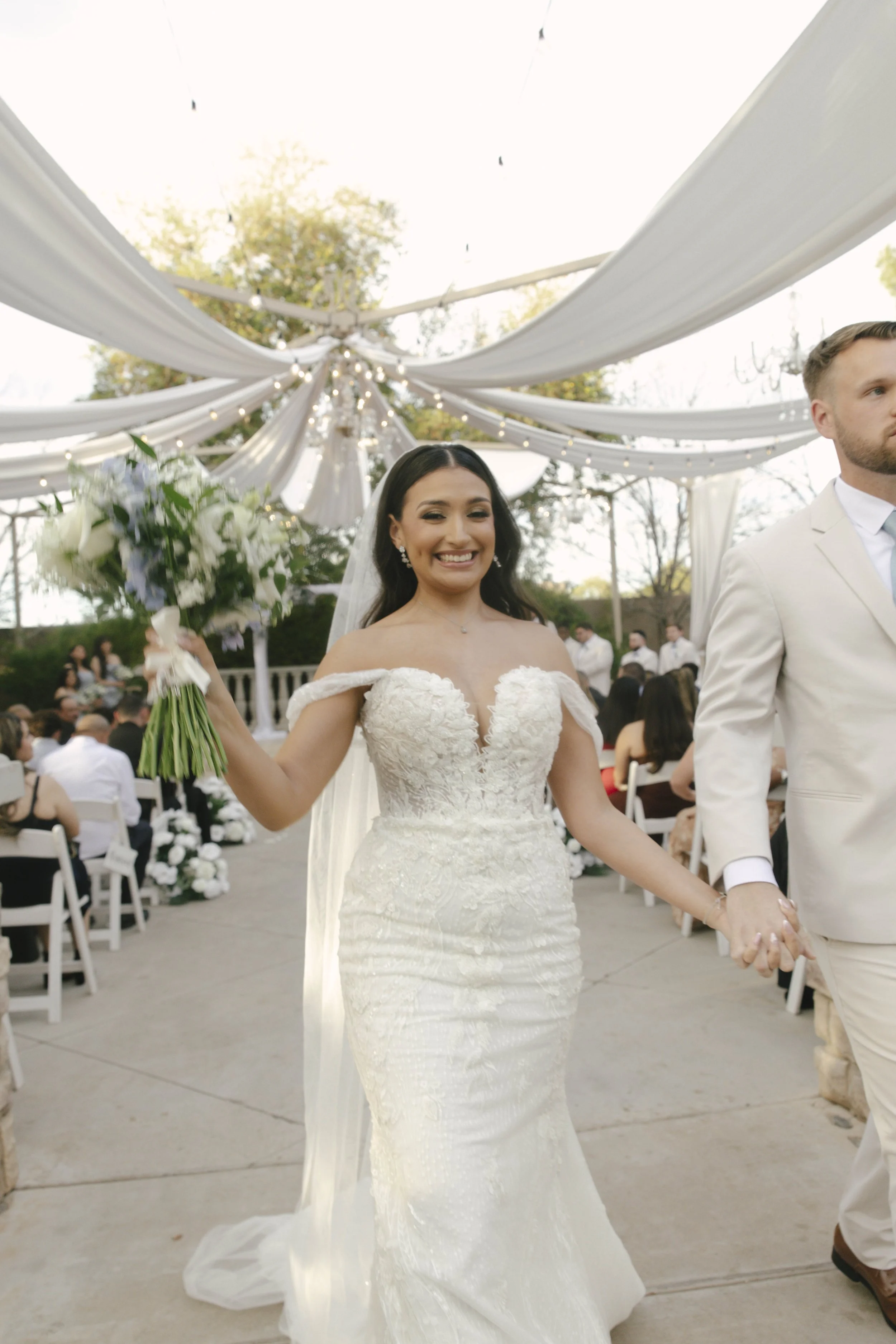 The bride and groom’s ceremony at Ashley Castle in Chandler, Arizona, was beautifully documented through hybrid film and digital photography, capturing their vows, ring exchange, and heartfelt moments beneath a romantic floral altar in the castle’s e