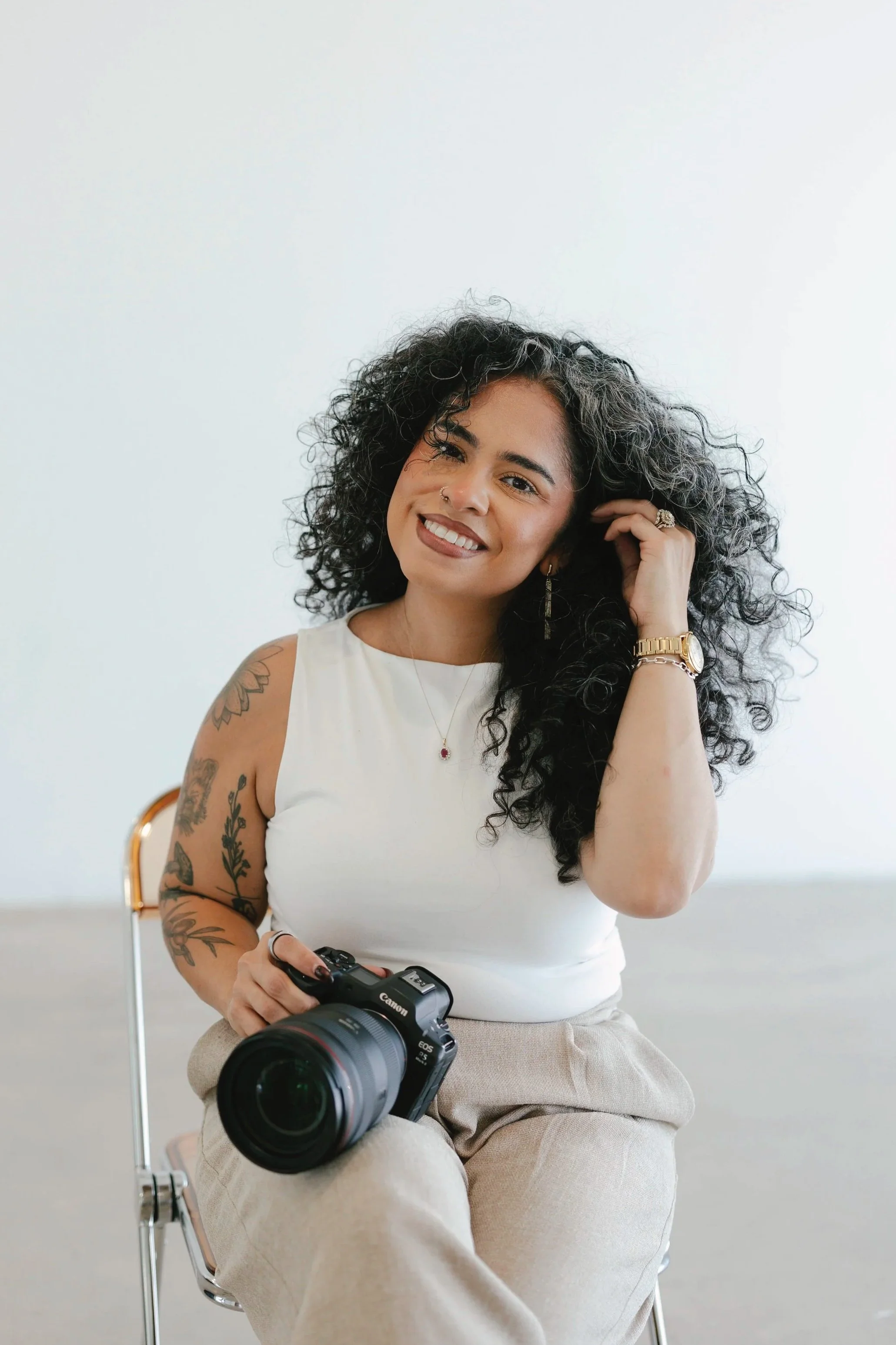 Portrait of Arizona wedding photographer Laura smiling while holding a camera in a bright, minimal studio setting