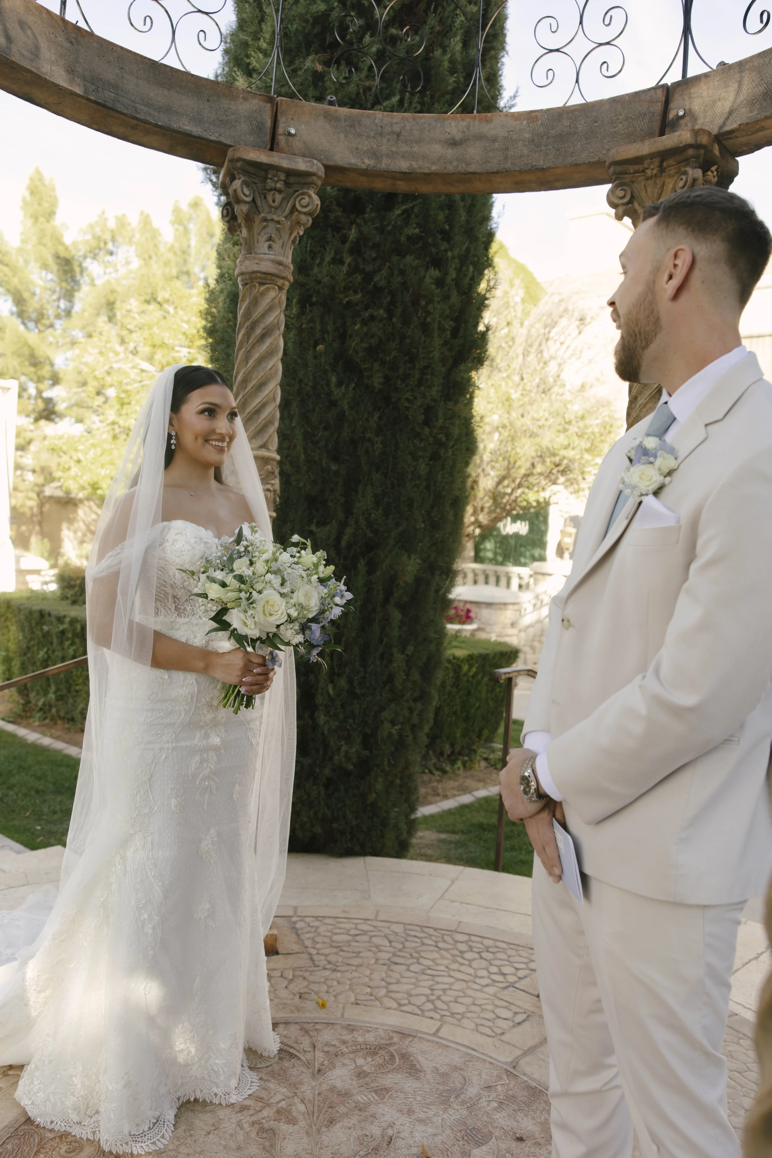 The bride and groom’s first look at Ashley Castle in Chandler, Arizona, unfolded in the venue’s romantic garden gazebo, where hybrid film and digital photography captured their emotional private reveal with timeless elegance, natural light, and intim