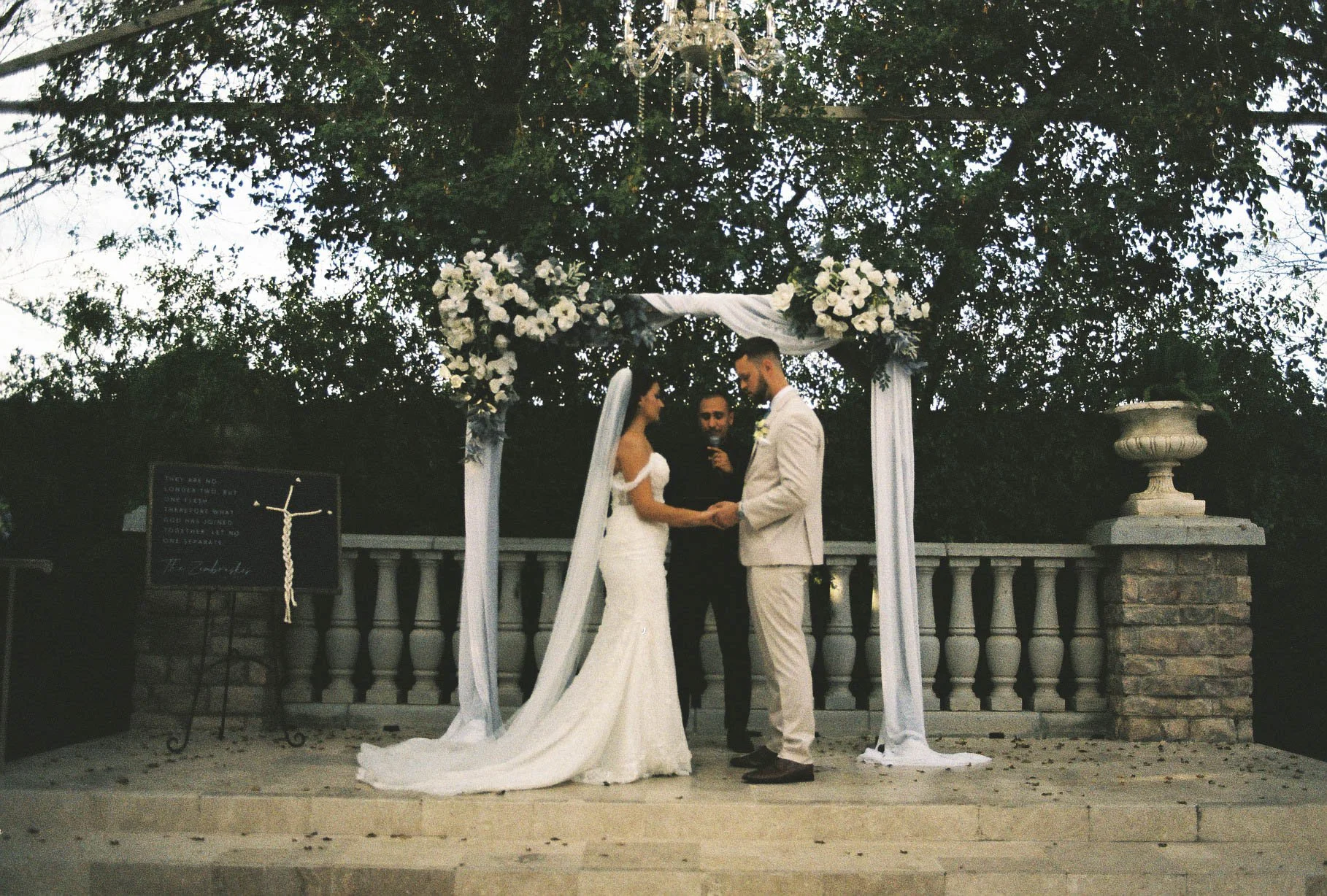 The bride and groom’s ceremony at Ashley Castle in Chandler, Arizona, was beautifully documented through hybrid film and digital photography, capturing their vows, ring exchange, and heartfelt moments beneath a romantic floral altar in the castle’s e