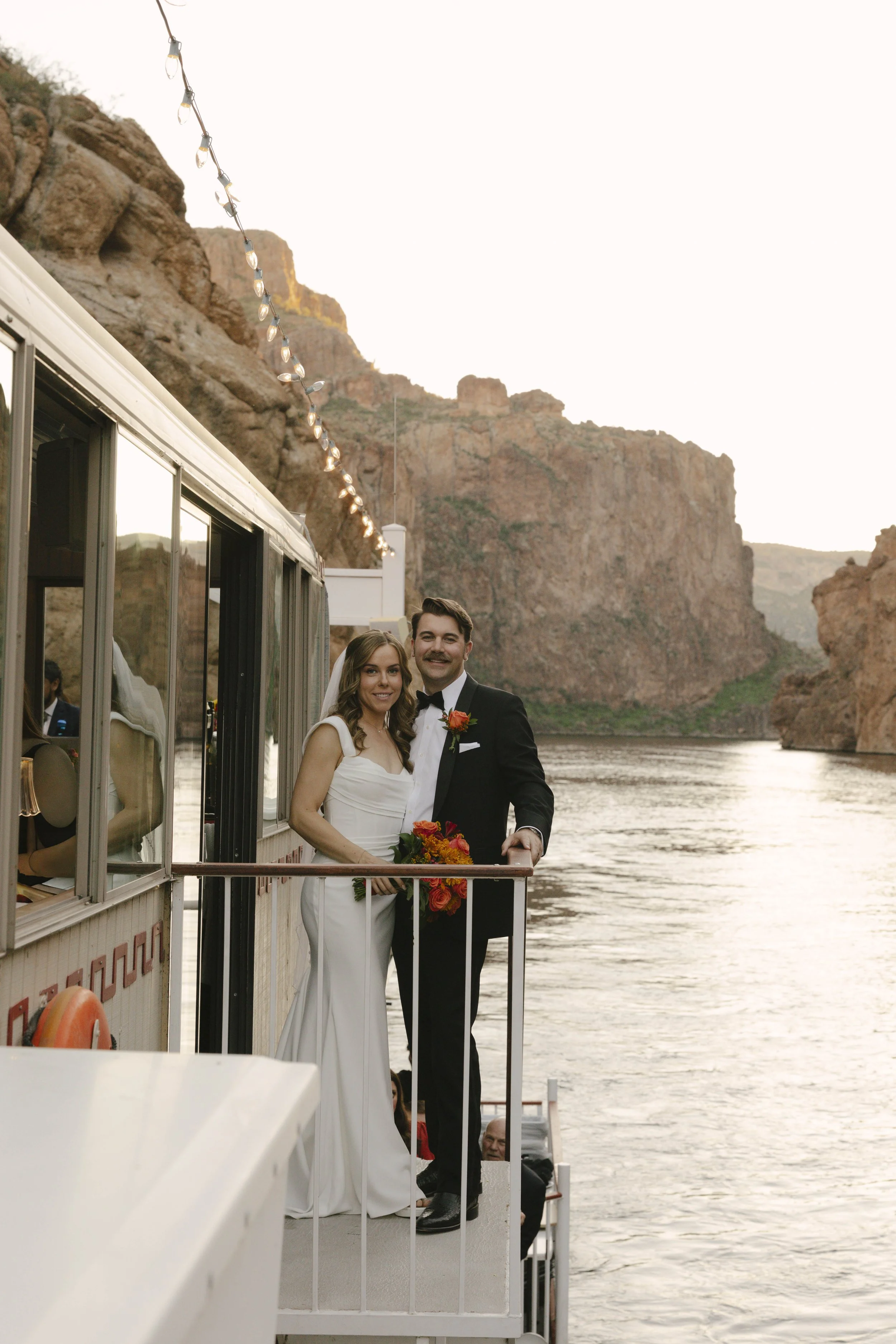 As the sun began to set over Canyon Lake, the couple stepped onto the deck of the Dolly Steamboat for golden hour portraits. With warm Arizona light reflecting off the water and desert mountains surrounding them, these quiet moments captured the beau