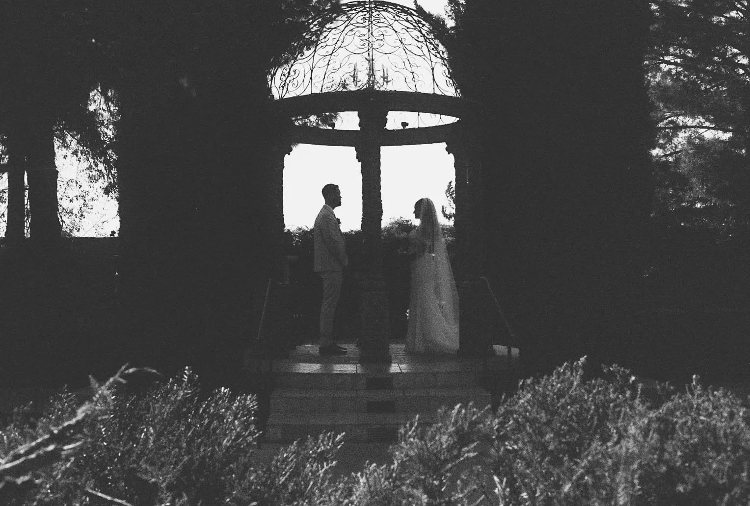 The bride and groom’s first look at Ashley Castle in Chandler, Arizona, unfolded in the venue’s romantic garden gazebo, where hybrid film and digital photography captured their emotional private reveal with timeless elegance, natural light, and intim