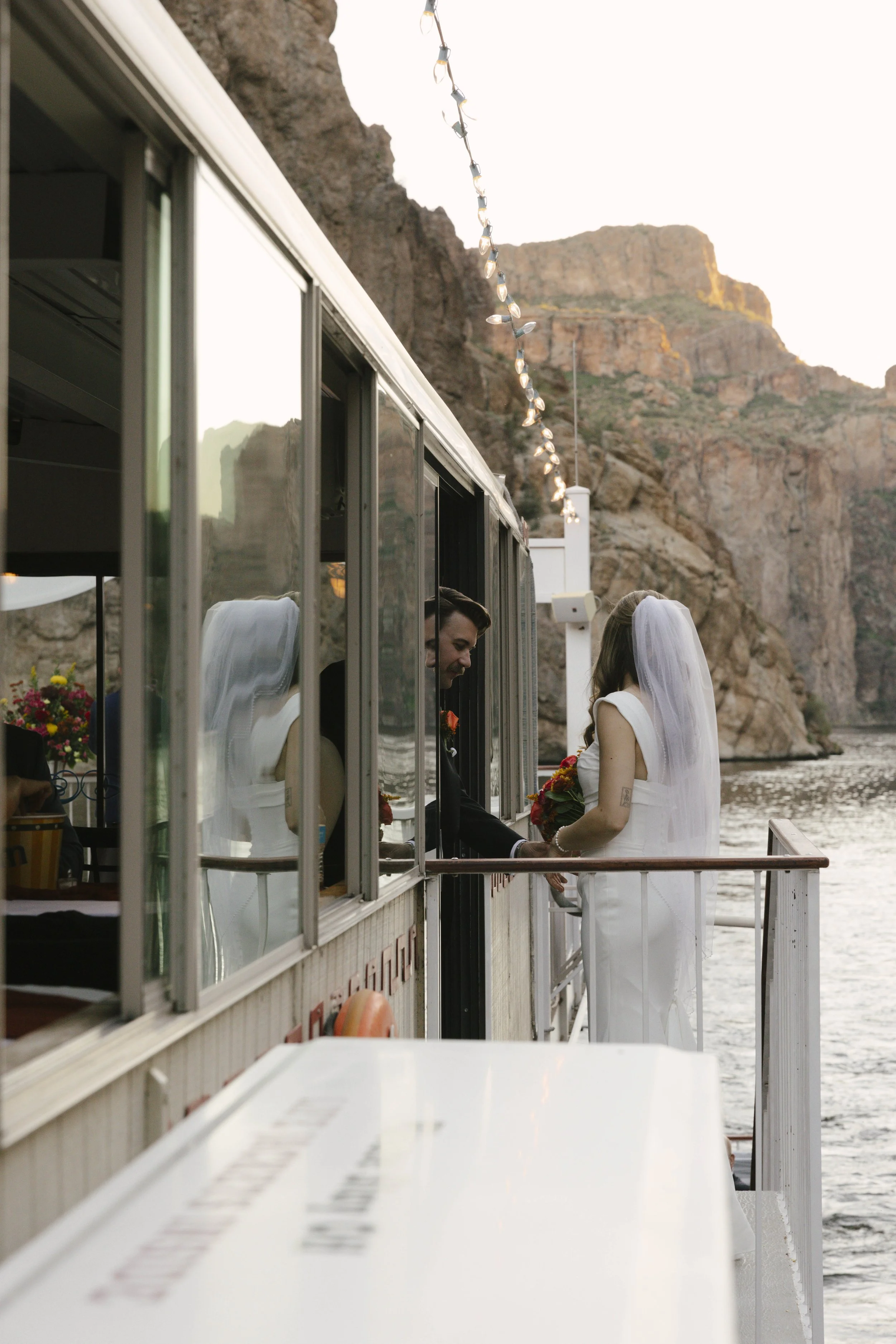 As the sun began to set over Canyon Lake, the couple stepped onto the deck of the Dolly Steamboat for golden hour portraits. With warm Arizona light reflecting off the water and desert mountains surrounding them, these quiet moments captured the beau
