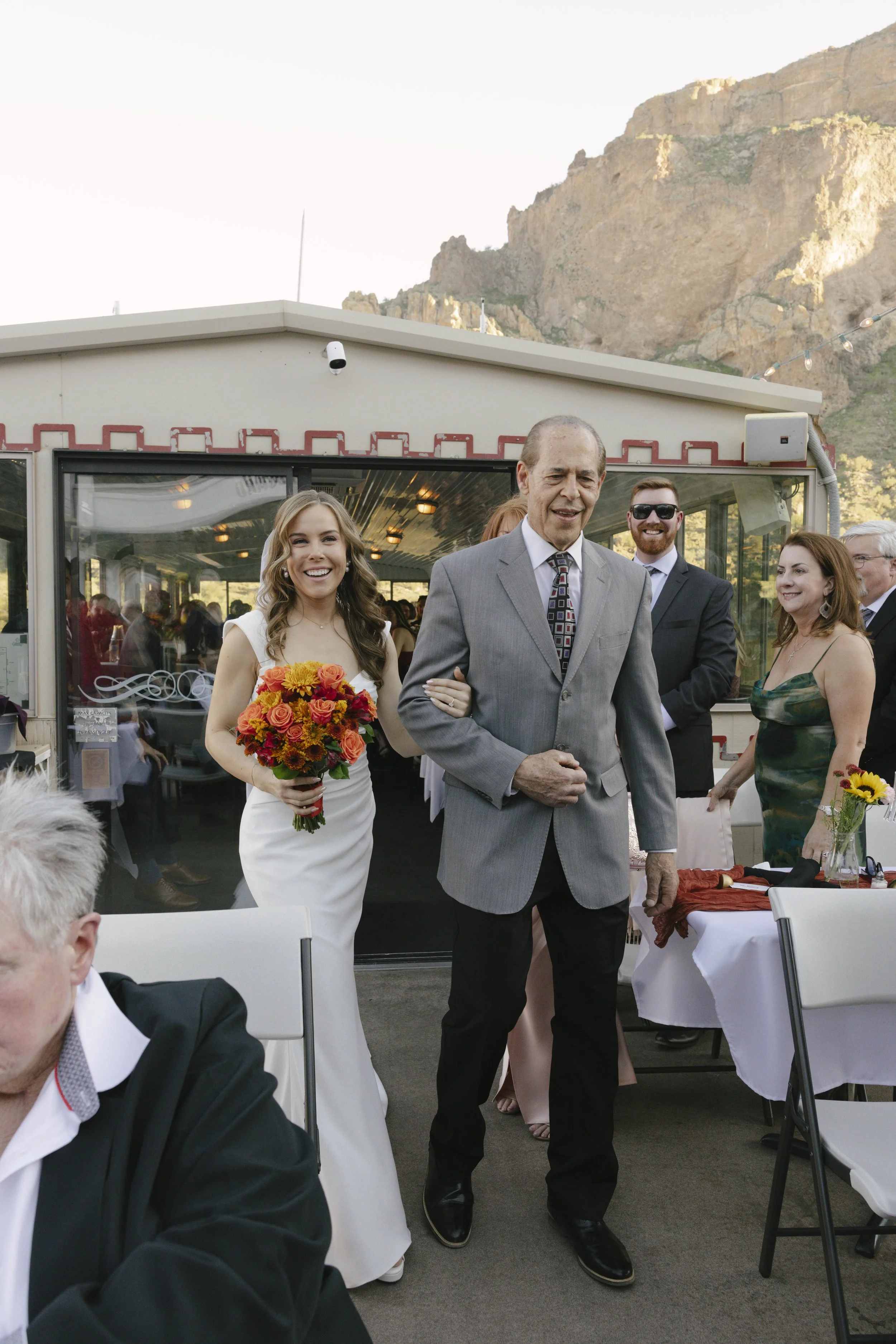 With Canyon Lake’s towering desert cliffs surrounding them, the couple exchanged rings and said “I do” aboard the Dolly Steamboat. Surrounded by about 60 of their closest friends and family, the ceremony took place on the deck with breathtaking Arizo