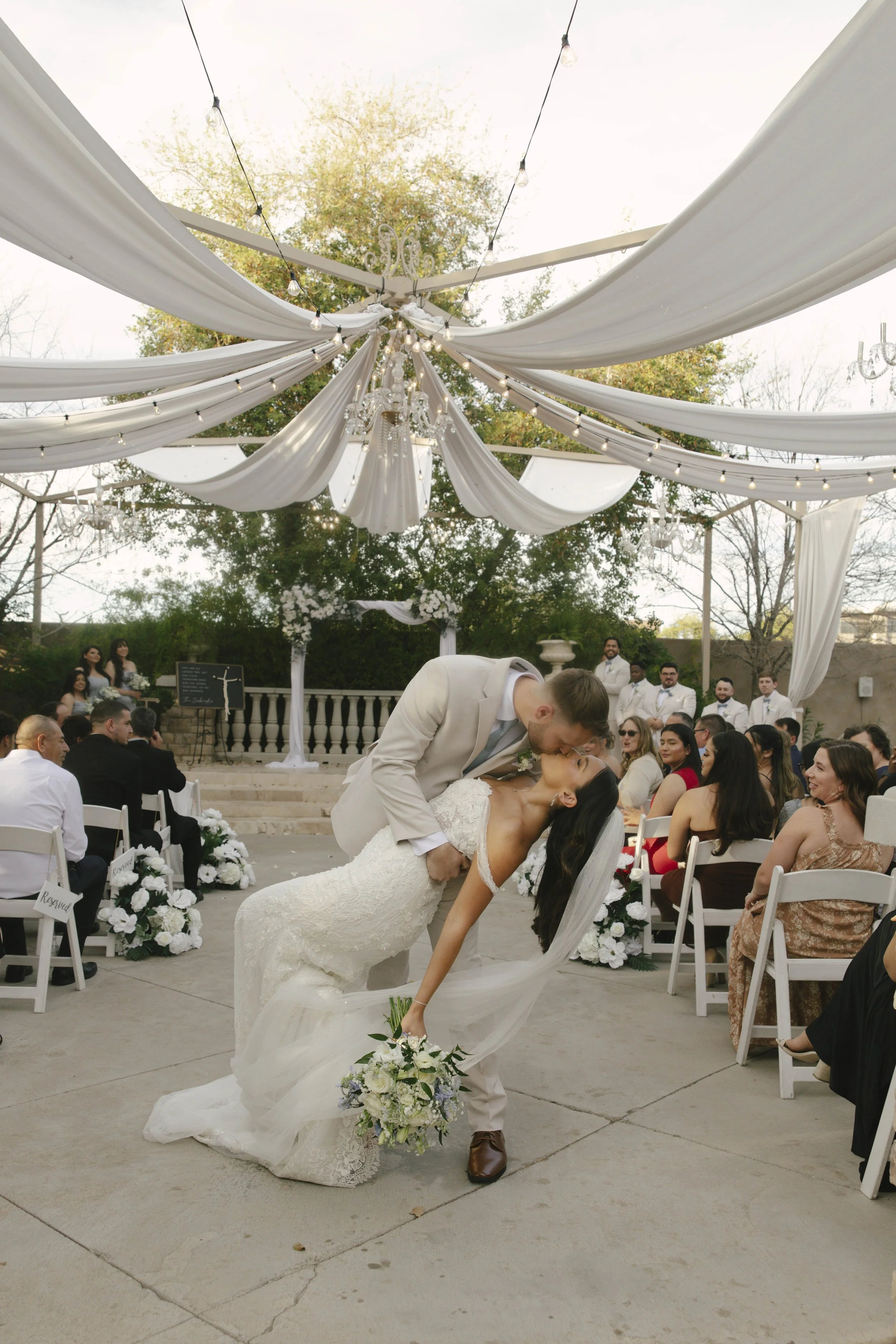 The bride and groom’s ceremony at Ashley Castle in Chandler, Arizona, was beautifully documented through hybrid film and digital photography, capturing their vows, ring exchange, and heartfelt moments beneath a romantic floral altar in the castle’s e